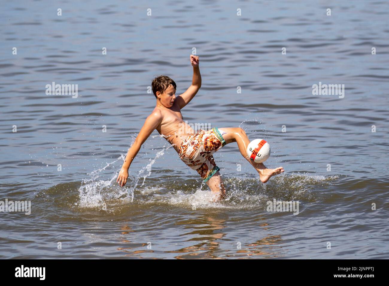 Southport, Merseyside, 12 August 2022 UK Weather. Cooling off at high tide, as temperatures reach 29C again.  Families enjoy the rare sight of the tide in at Southport, on a sweltering sunny summer’s day. Today will be another fine and dry day with extensive spells of sunshine. It will be very warm, for all. Credit:MediaWorldImages/AlamyLiveNews. Stock Photo