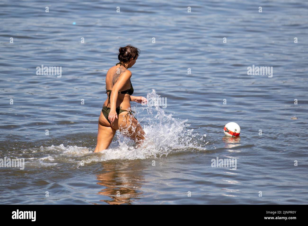 Beach games in Southport, Merseyside, August 2022 UK Weather. Cooling off at high tide, as temperatures reach 29C again.  Families enjoy the rare sight of the tide in at Southport, on a sweltering sunny summer’s day. Today will be another fine and dry day with extensive spells of sunshine. It will be very warm, for all. Credit:MediaWorldImages/AlamyLiveNews. Stock Photo