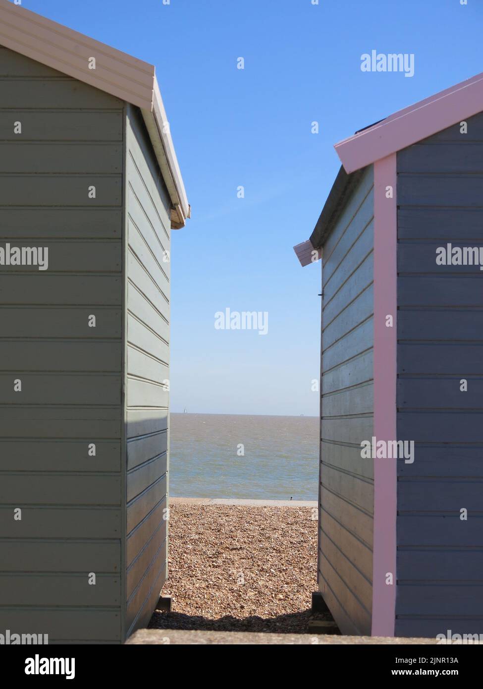 View of the beach, sea, horizon and blue sky visible between two