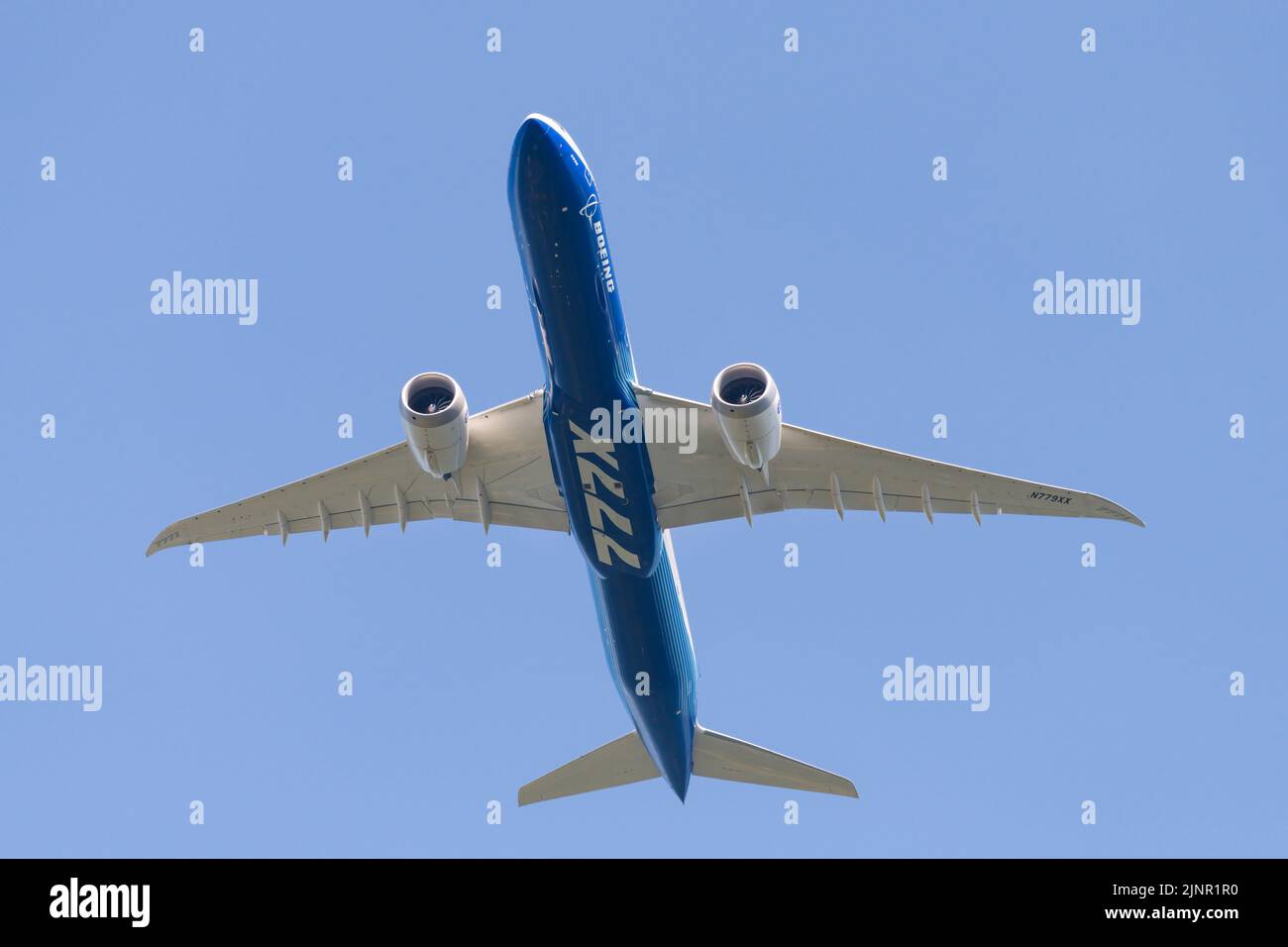 Seattle - August 12, 2022; Boeing 777X aircraft viewed from below in flight isolated againt clear blue sky in company livery Stock Photo