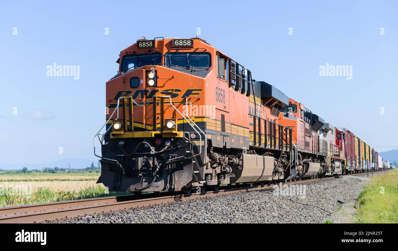 Stanwood, WA, USA - August 11, 2022; BNSF mixed freight train passing through Western Washington State against blue sky Stock Photo