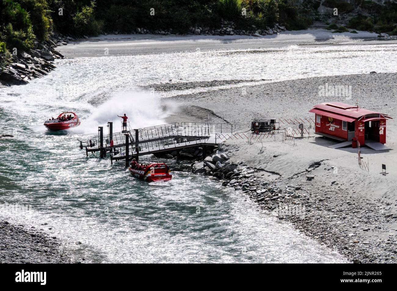 View of the high speed jet boat on the river Shootover close to the 'check in ' cabin on the shore. Queenstown on South Island, New Zealand Stock Photo