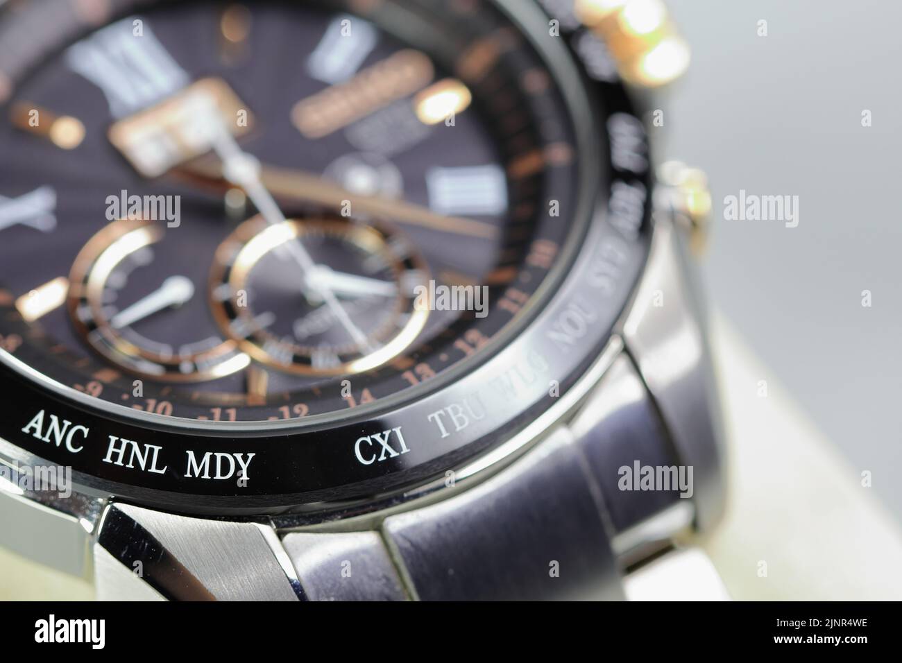 close up shallow focus Time zone cities code on luxury world time watch bezel on ANC  Anchorage, HNL Honolulu, MDY Midway, CXI Kiribati. Stock Photo