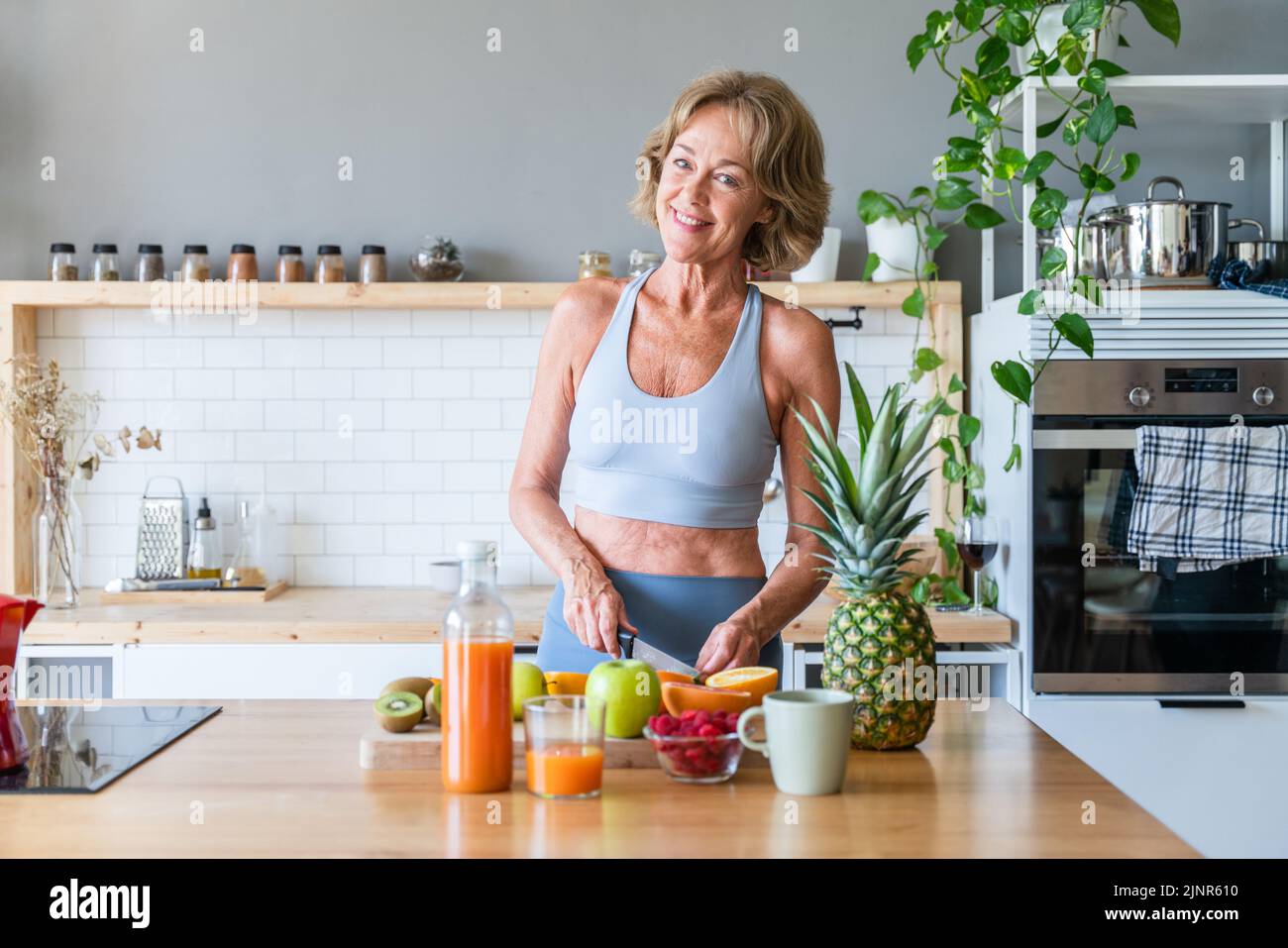 Beautiful mature senior woman at home, domestic life and leisure moments - 50-60 years old pretty female adult wearing sportswear eating healthy food Stock Photo