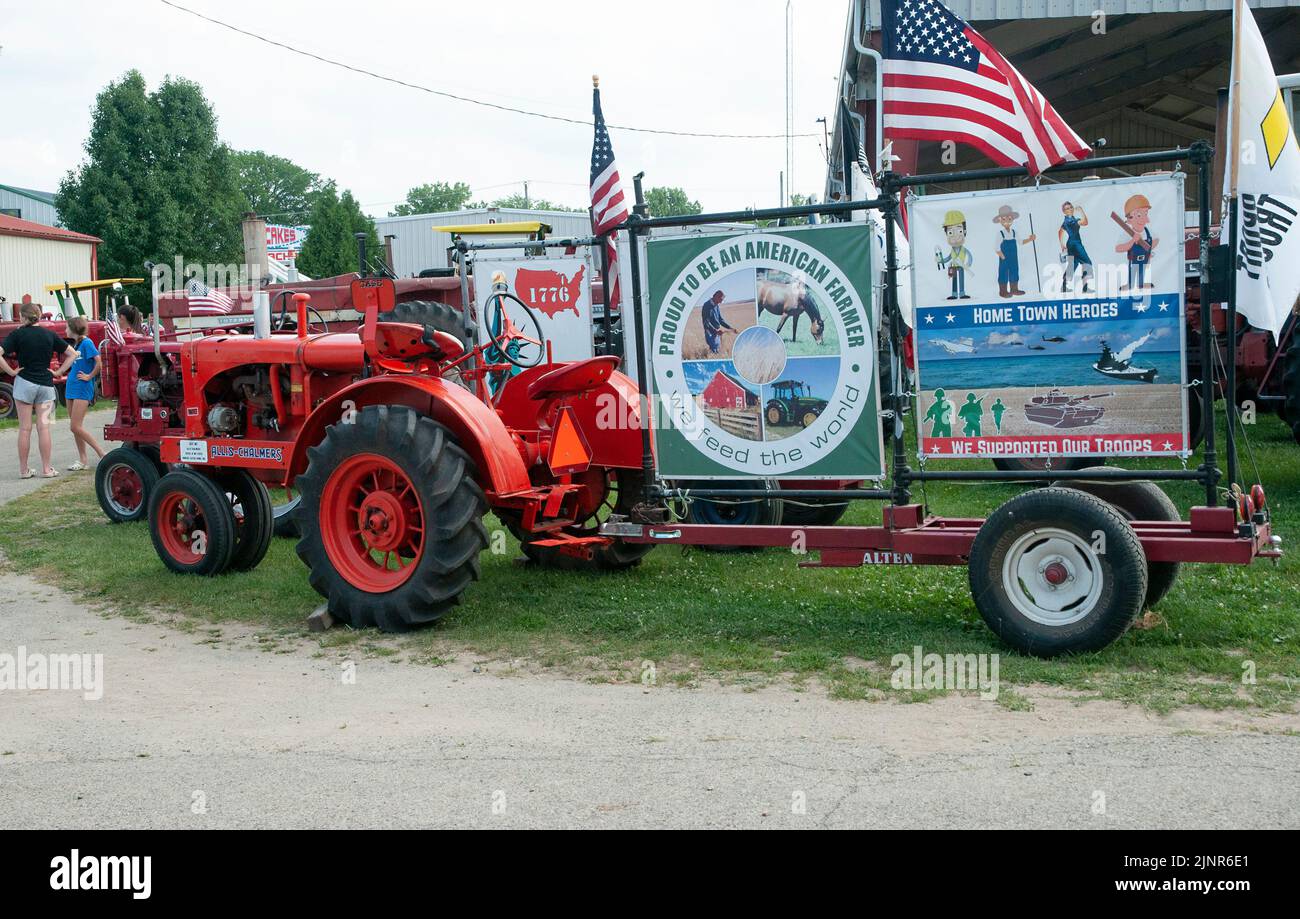 Antique farm tractor hitched to pro farming bulletin board. Stock Photo