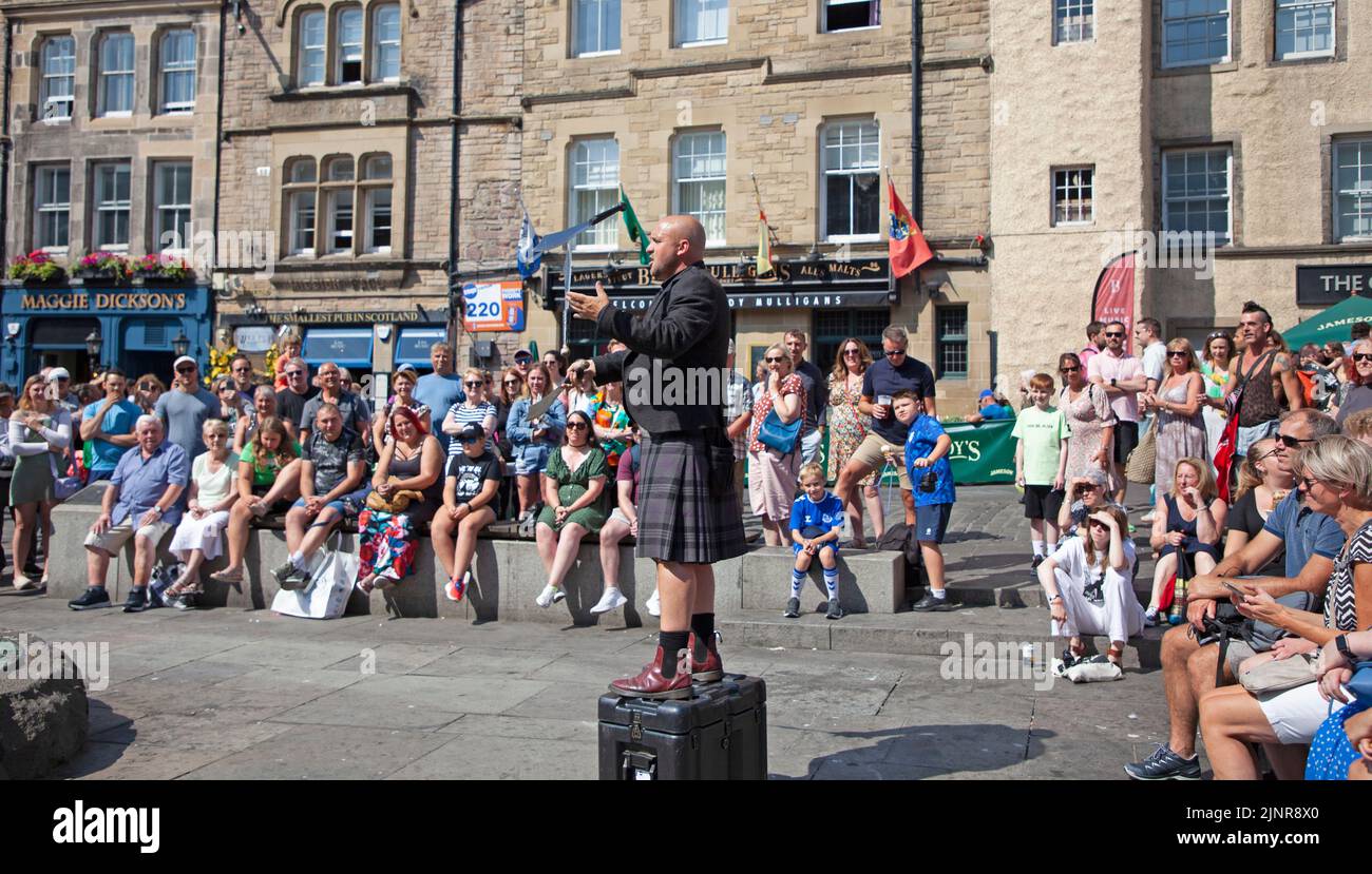 Edinburgh city centre, Scotland, UK. 13th August 2022. 9th Day for the Edinburgh Festival Fringe and the Film and Book festival also began this weekend so very busy with visitors enjoying the temperature of 22 degrees centigrade befor the haar arrived from the east coast mid afternoon. Pictured: Pete Anderson street performer entertaining an audience in The Grassmarket.  Credit: ArchWhite/alamy live news. Stock Photo