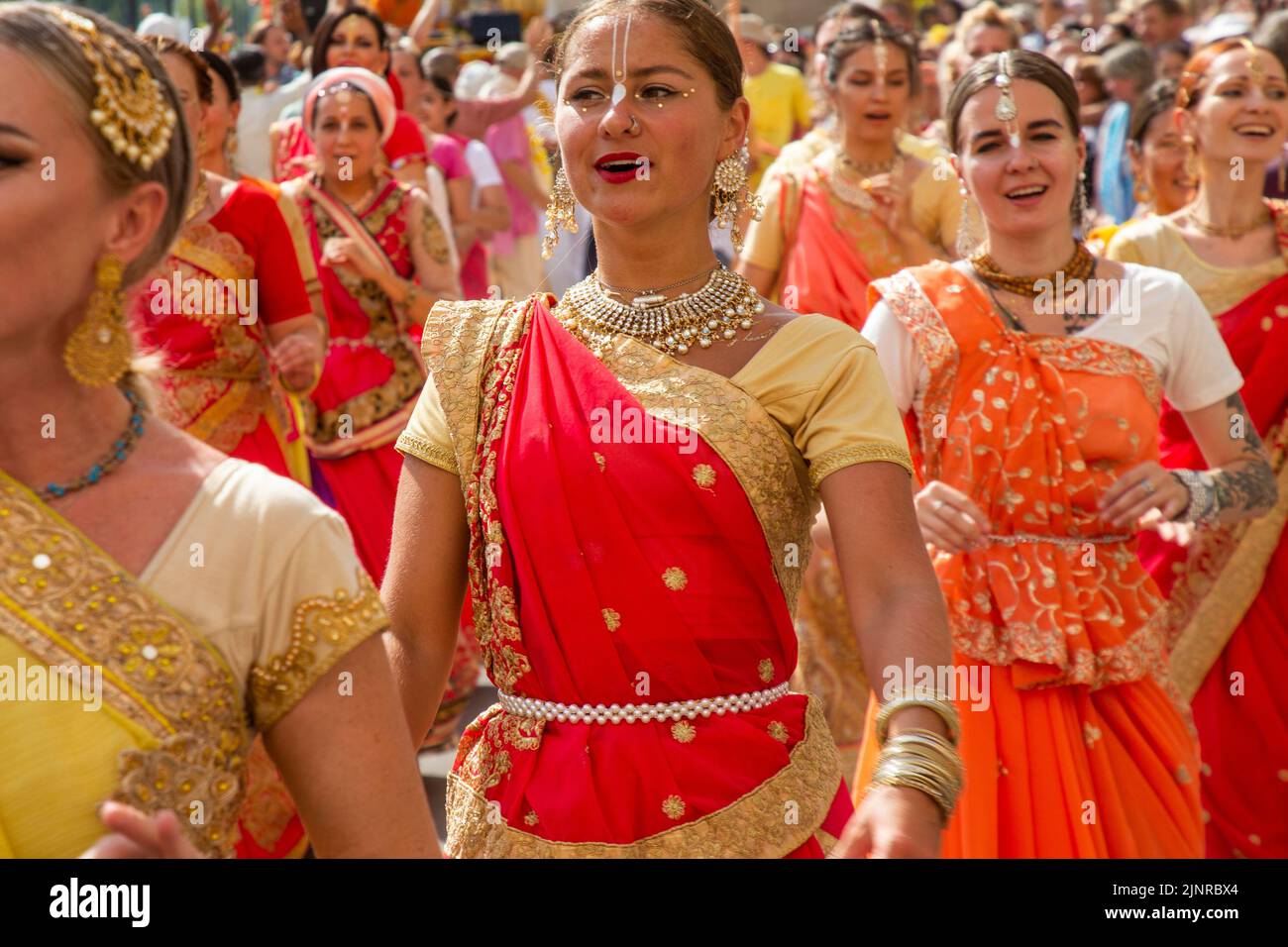 Moscow, Russia. 13th of August, 2022. Russian women in Indian national costumes sing 'Hare Krishna' and dance at the head of the procession of the Ratha Yatra parade, or the Hindu religious Chariot Festival, as part of the India Day festival taking place in Dream Island Park of Moscow, Russia Stock Photo