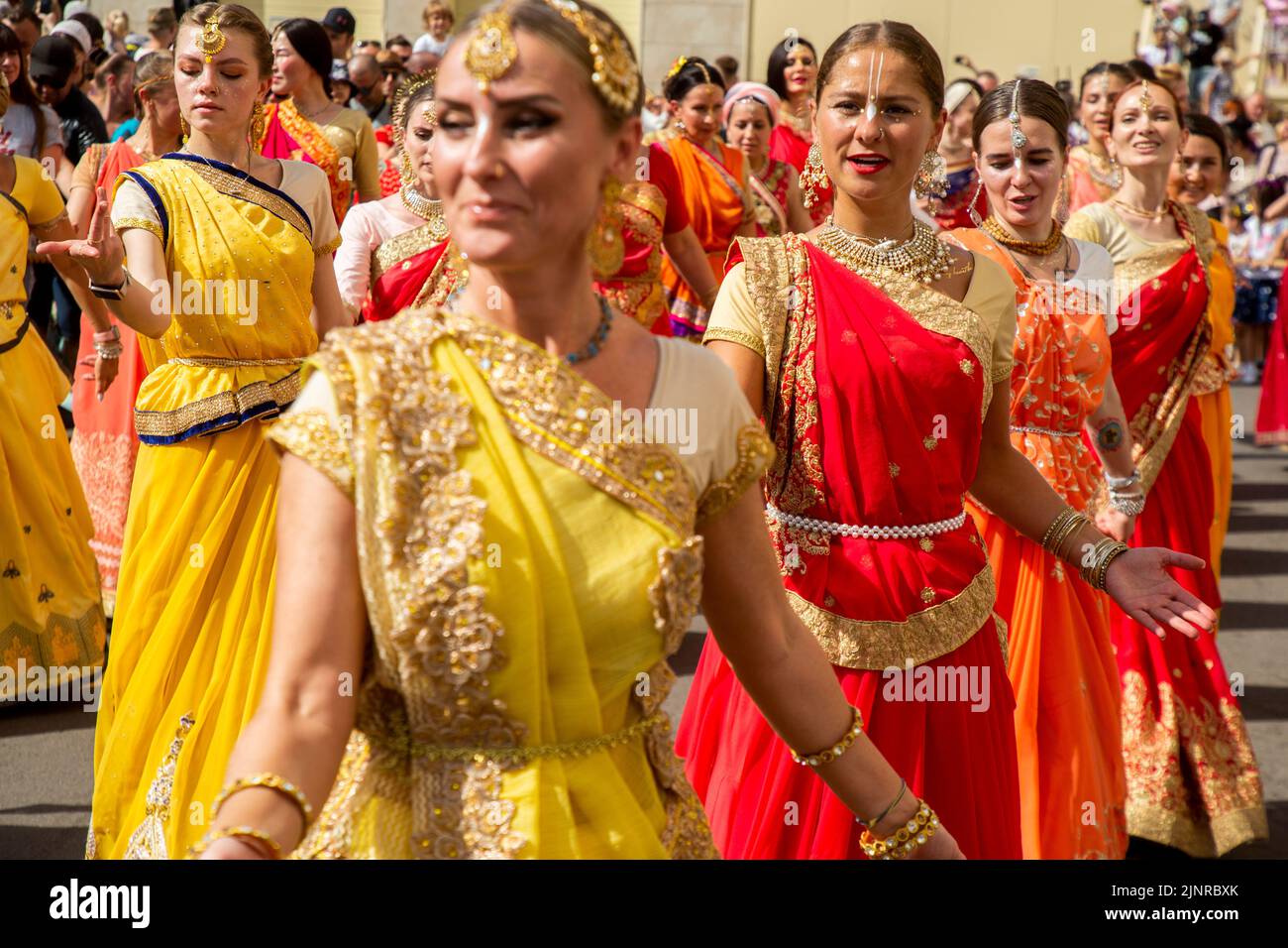 Moscow, Russia. 13th of August, 2022. Russian women in Indian national costumes sing 'Hare Krishna' and dance at the head of the procession of the Ratha Yatra parade, or the Hindu religious Chariot Festival, as part of the India Day festival taking place in Dream Island Park of Moscow, Russia Stock Photo