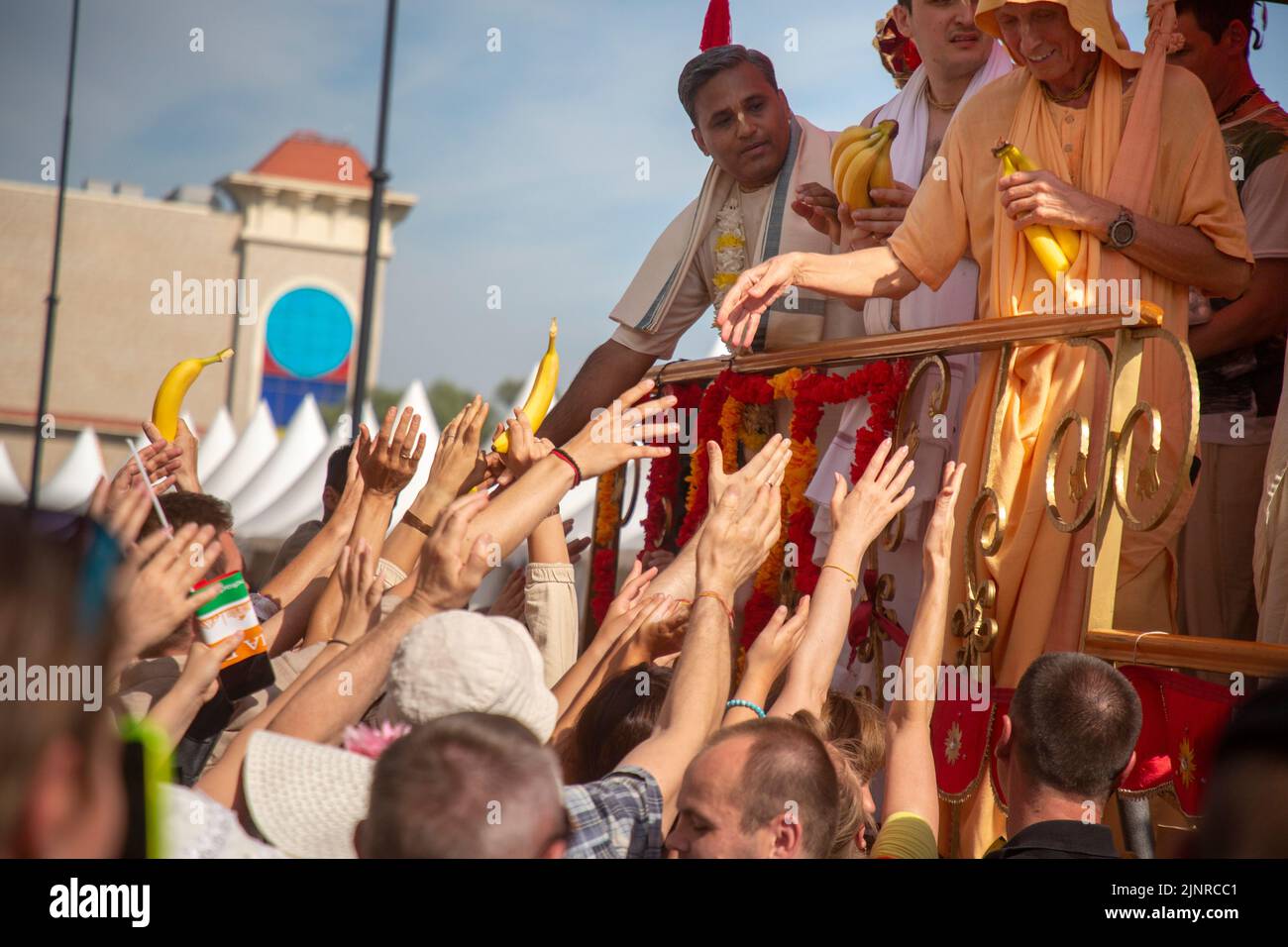 Moscow, Russia. 13th of August, 2022. Сlergy hands out exotic fruits to devotees from the main float cart during the celebration Hare Krishna Ratha Yatra parade, or the Hindu religious Chariot Festival, as part of the India Day festival in the Dream Island Park, Russia Stock Photo