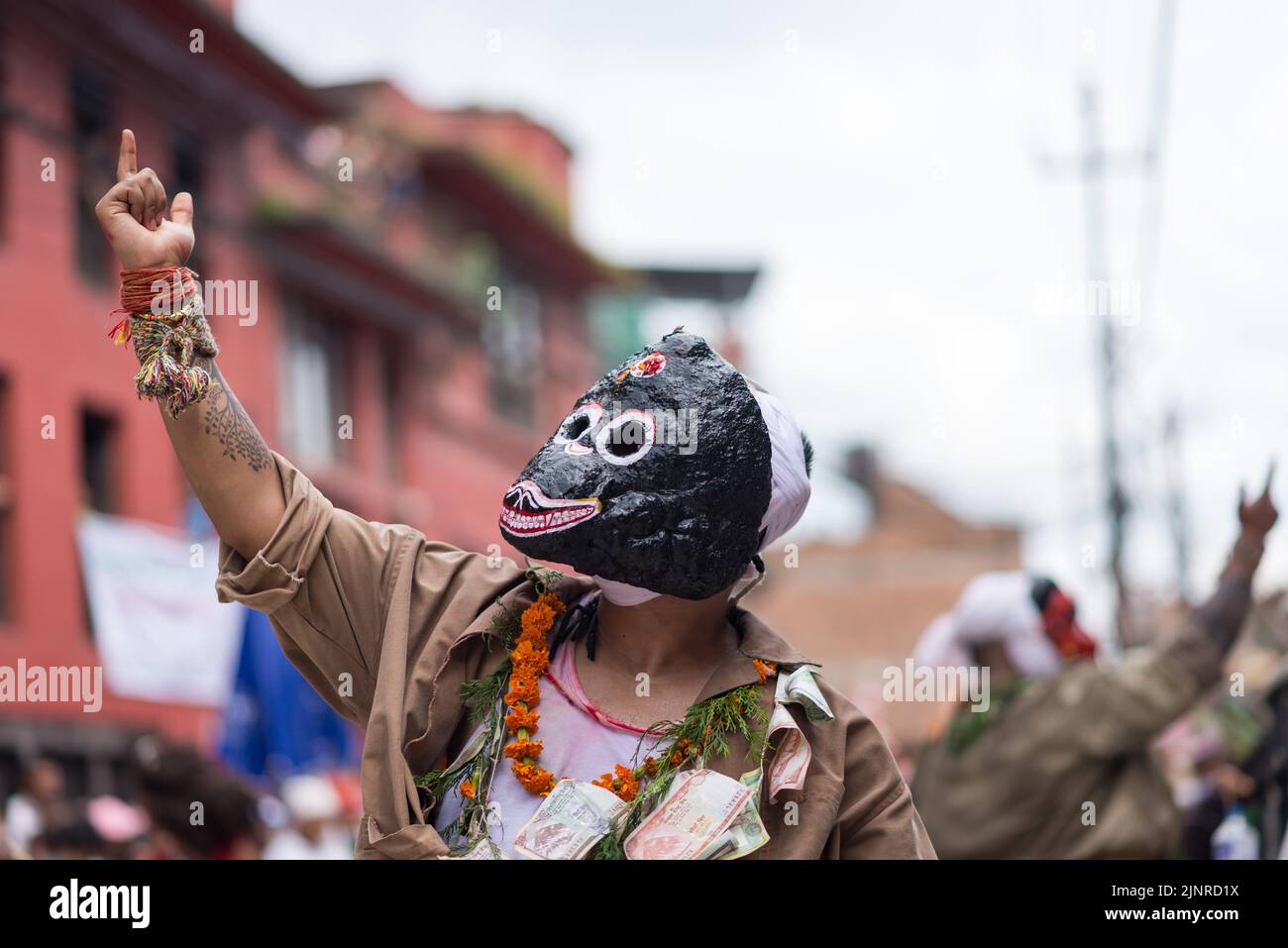 A man dressed in a traditional costume performs a holy dance during the festival. People celebrate Gai Jatra or cow festival in memory of the departed souls in the past year for salvation and peace. It is believed that cows guide the departed souls to cross the river to get to heaven. Stock Photo