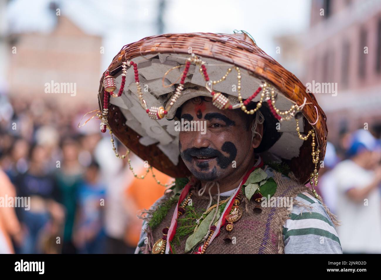A man with painted face seen during the Gai Jatra or cow festival procession. People celebrate Gai Jatra or cow festival in memory of the departed souls in the past year for salvation and peace. It is believed that cows guide the departed souls to cross the river to get to heaven. Stock Photo