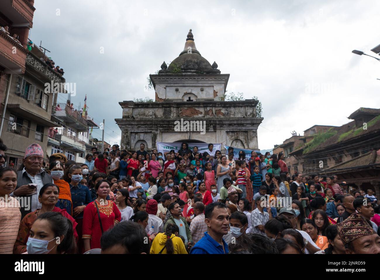 People gathered around the temple to watch the Gai Jatra dance and procession during the festival. People celebrate Gai Jatra or cow festival in memory of the departed souls in the past year for salvation and peace. It is believed that cows guide the departed souls to cross the river to get to heaven. Stock Photo