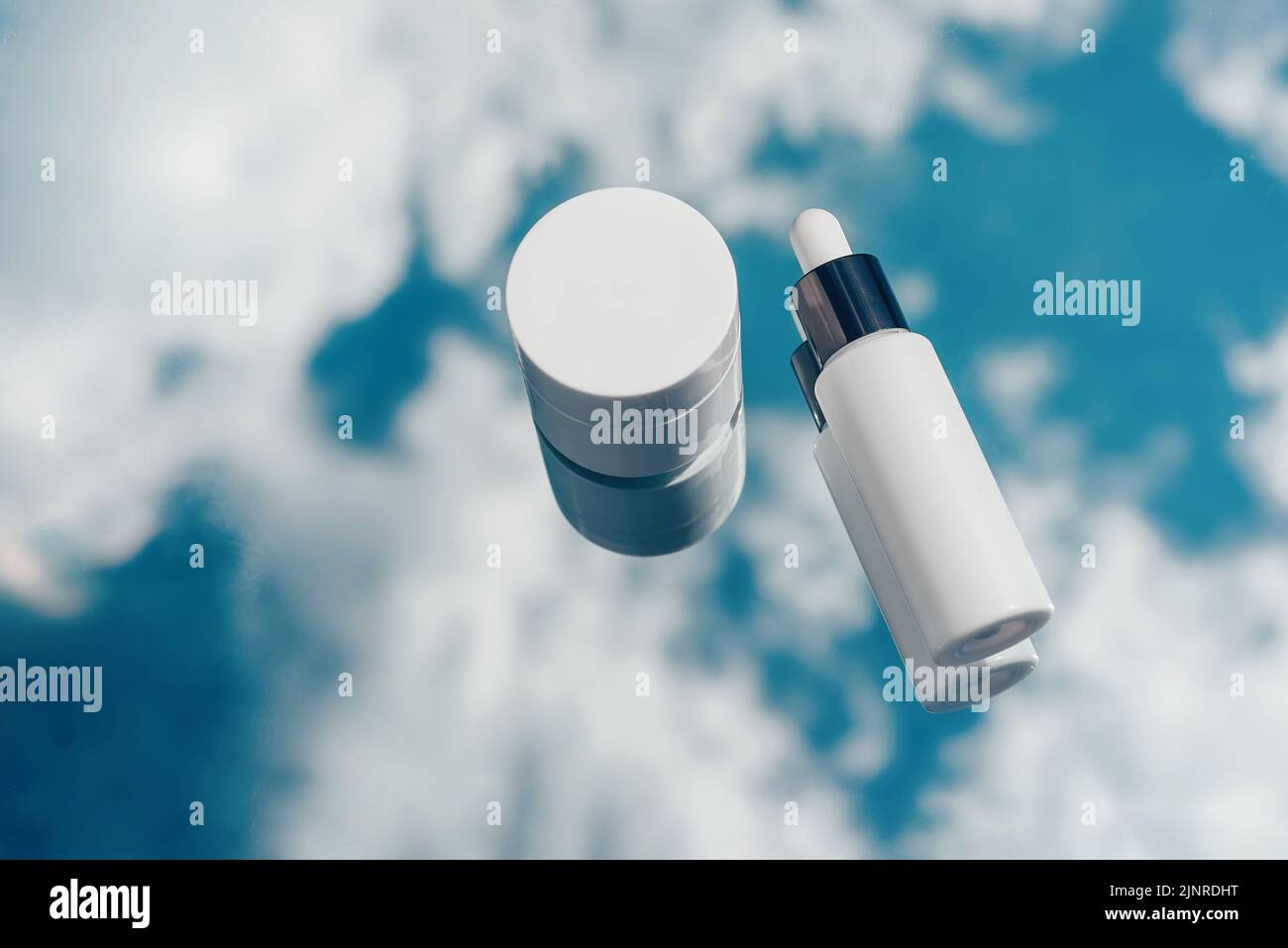 Natural oxygen cosmetics, white mockup of a bottle with a pipette, jar of cream, blue sky background Stock Photo