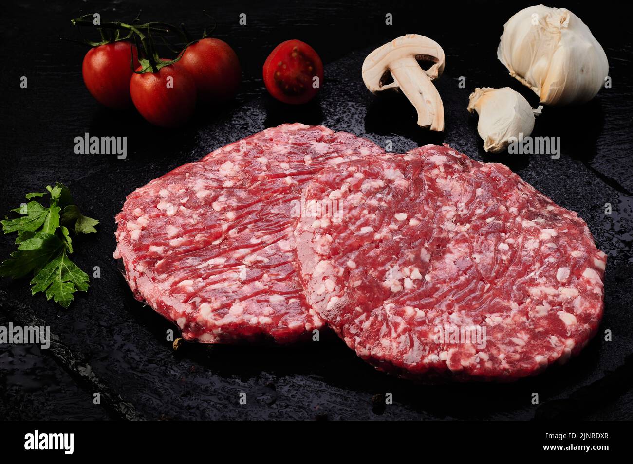 Raw burger, tomatoes, mushrooms and garlic Stock Photo