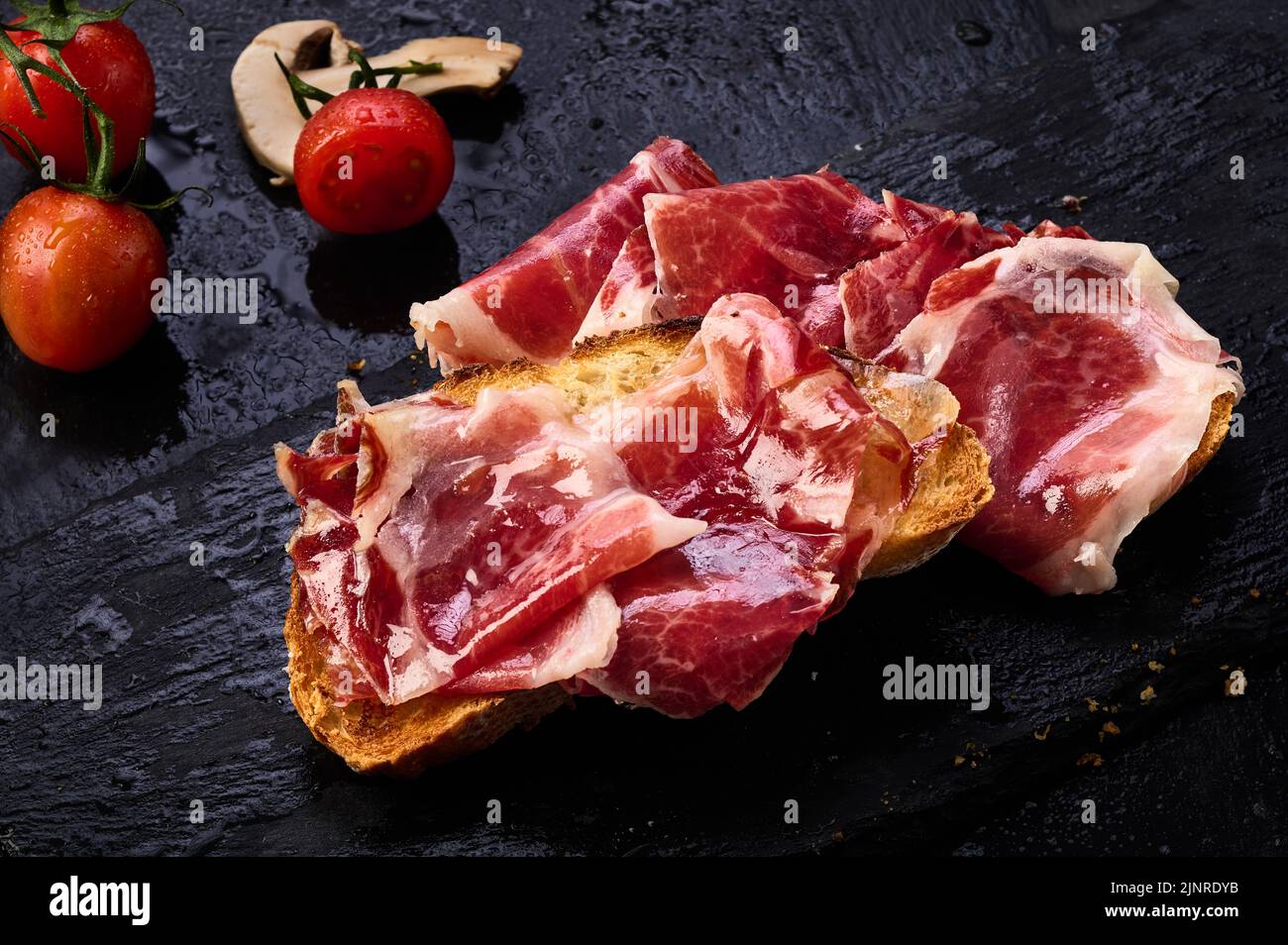 Iberian ham slices on a slice of toasted bread Stock Photo - Alamy