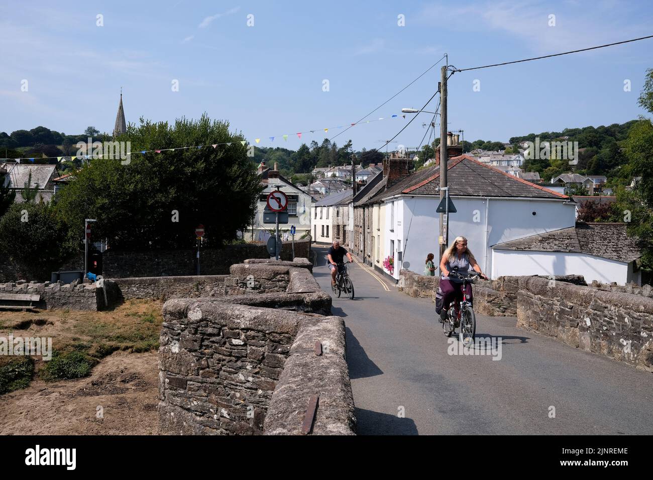 two cyclists crossing a tudor bridge in lostwithiel town,cornwall,uk august 2022 Stock Photo