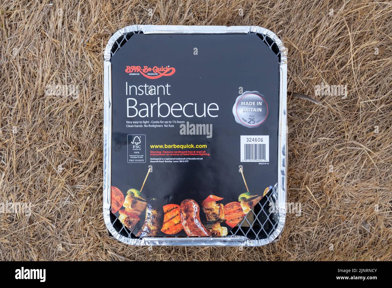 Disposable barbecue placed on parched brown grass, heatwave and drought in August 2022, UK. Concept - risk of fire, fires, wildfires Stock Photo