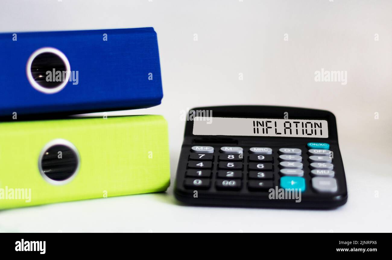 The word INFLATION on the calculator looks at interest rate increases, the global economy, and inflation control. Stock Photo