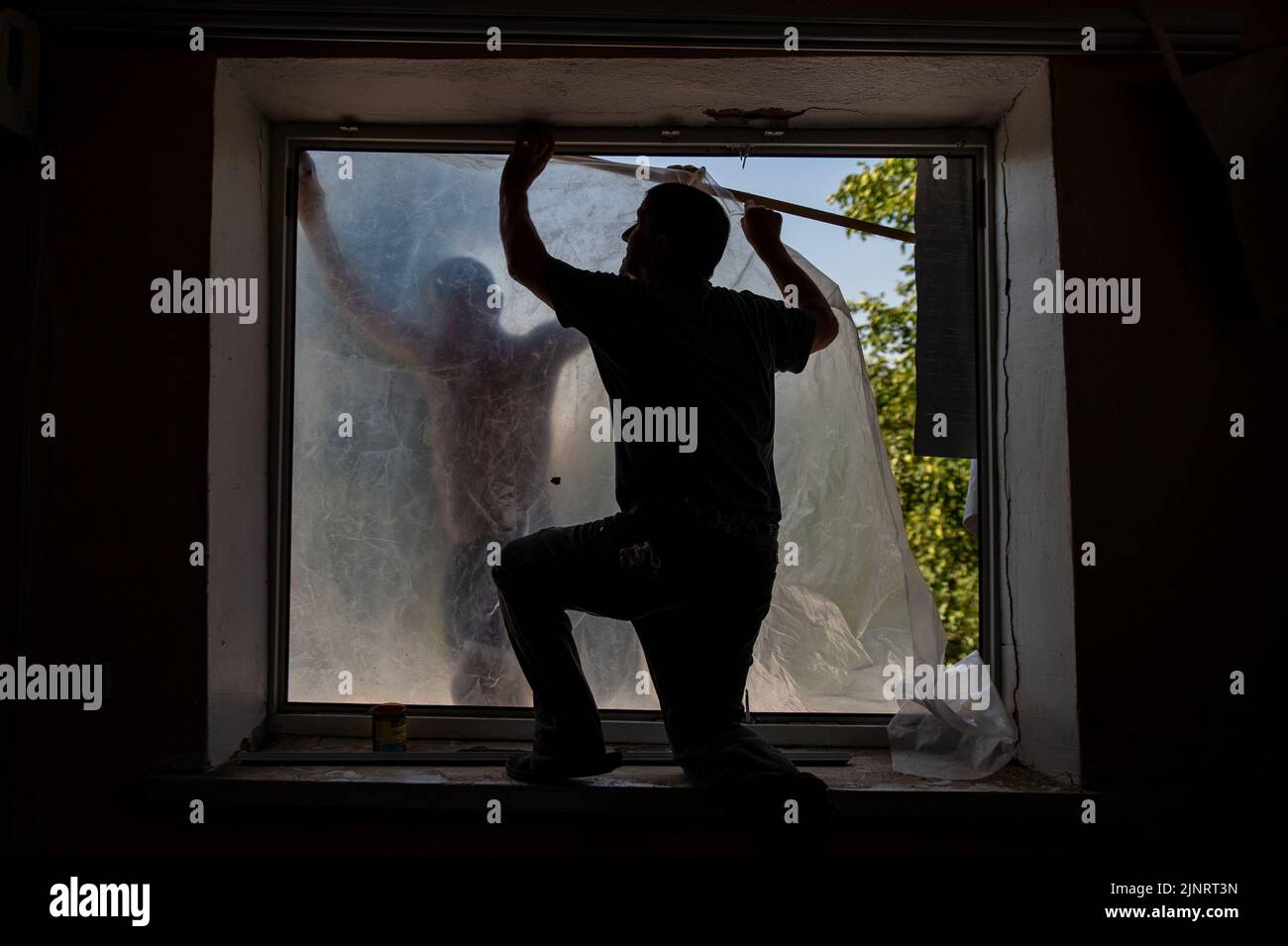 Men work to make repairs to the window in Kushuhum after being blown out by shelling days before. The small village outside Zaporizhzhia has been home to shelling the past days killing at least one. Stock Photo