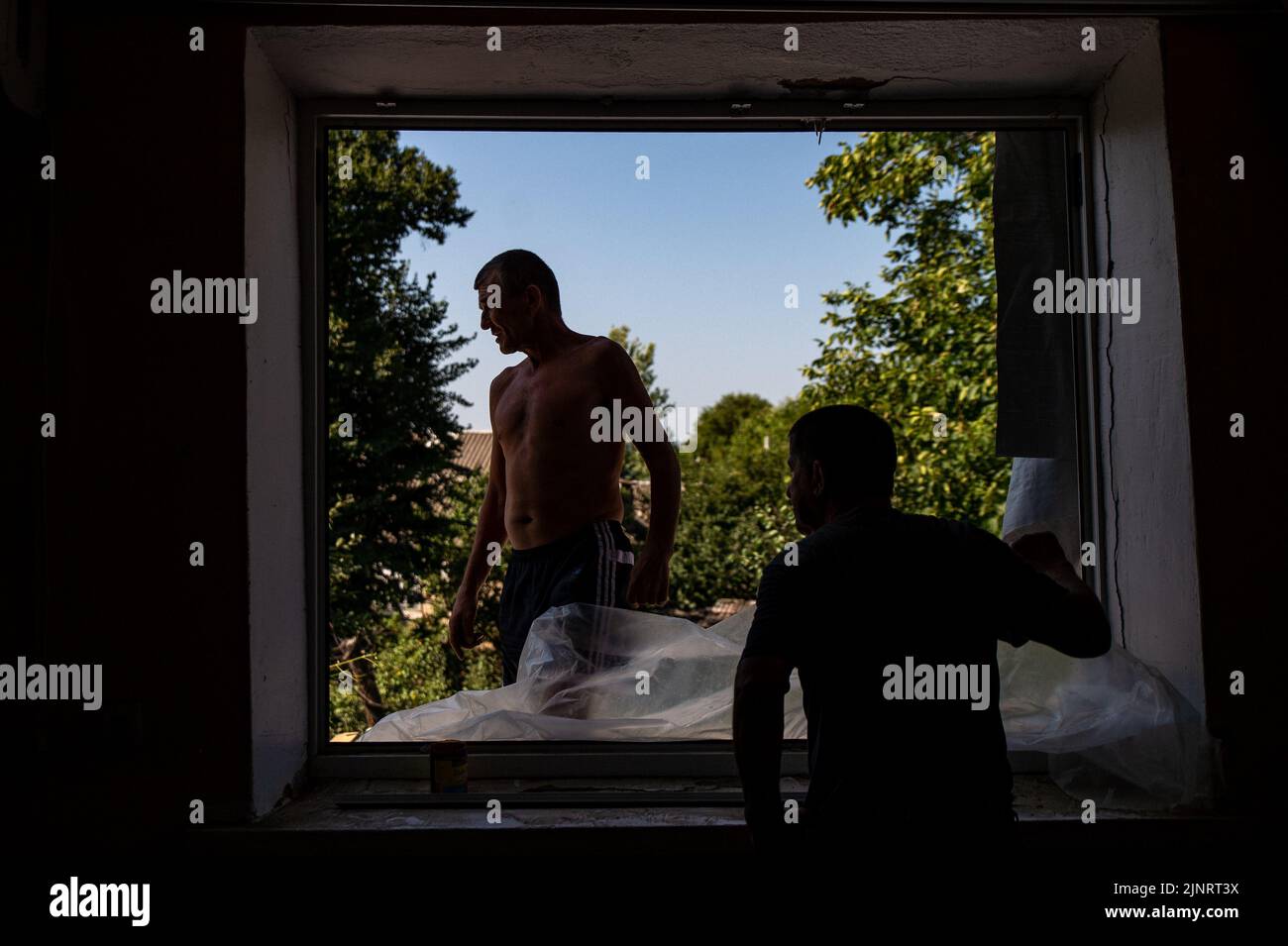 Men work to make repairs to the window in Kushuhum after being blown out by shelling days before. The small village outside Zaporizhzhia has been home to shelling the past days killing at least one. Stock Photo