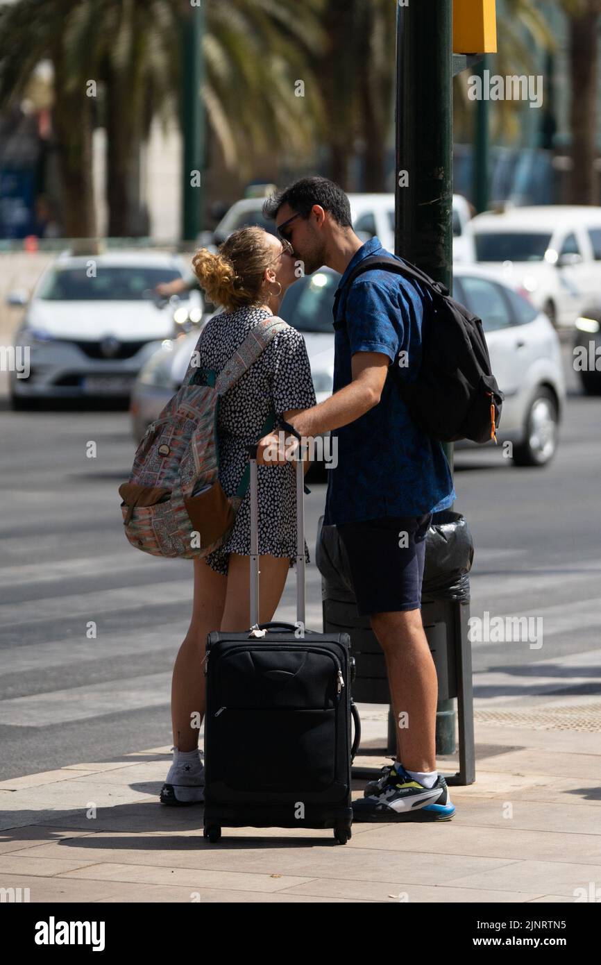 A couple with a suitcase seen kissing during the first day of Malaga's Fair 2022. The Fair is being held for the first time since 2019. The 2020 and 2021 editions were suspended due to Covid19 pandemic. Stock Photo