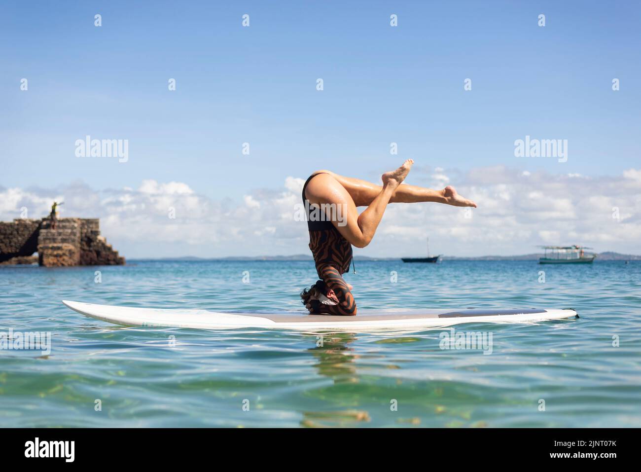 Salvador, Bahia, Brazil - June 04, 2022: Woman stands upside down on a surfboard at Porto da Barra beach in Salvador, Bahia. Stock Photo