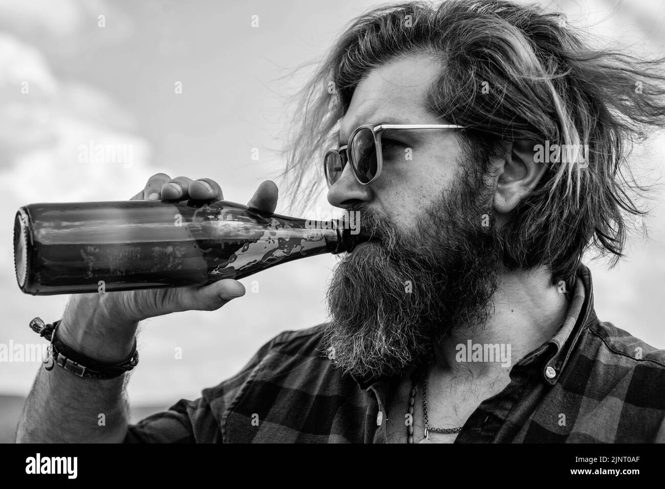 hydration concept. bearded man in checkered shirt drink water from bottle. casual guy drinking beer. brutal hipster with long hair and moustache relax Stock Photo