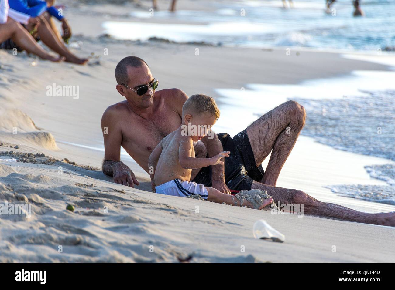 A Cuban, man in his 30's with his child playing on the beach, Varadero, Beach, Cuba. Stock Photo
