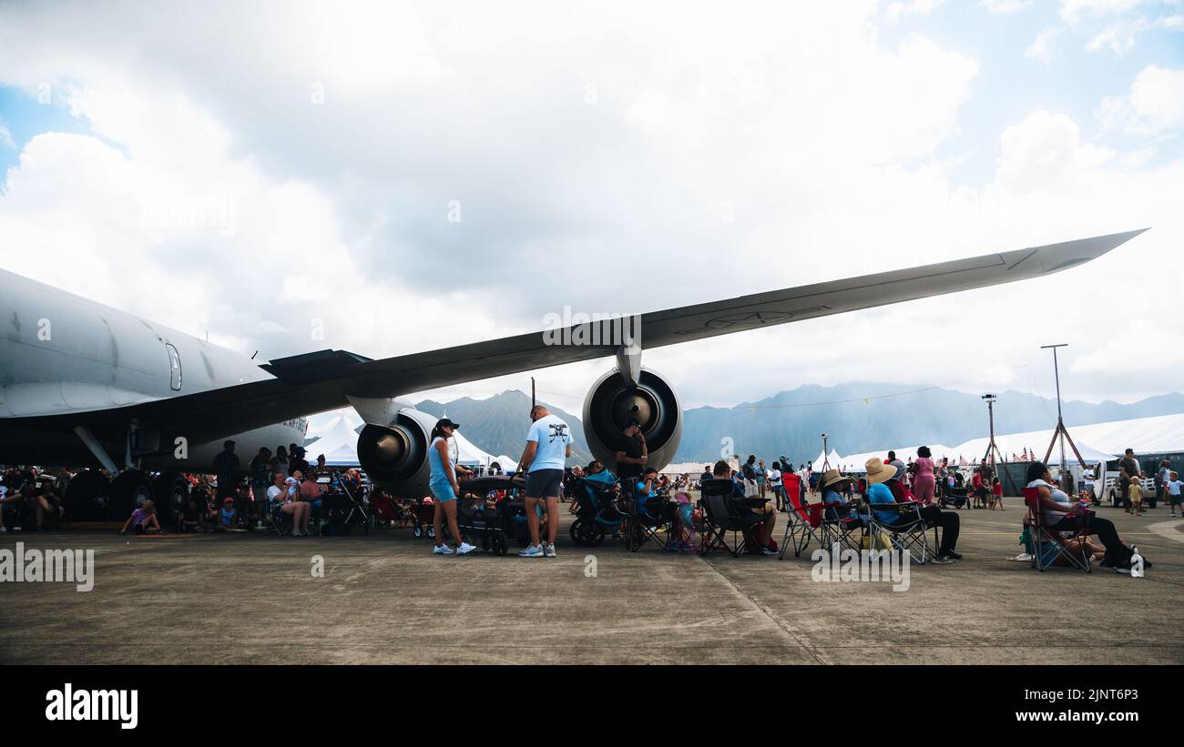 Families sit under the shade of a static display at the 2022 Kaneohe