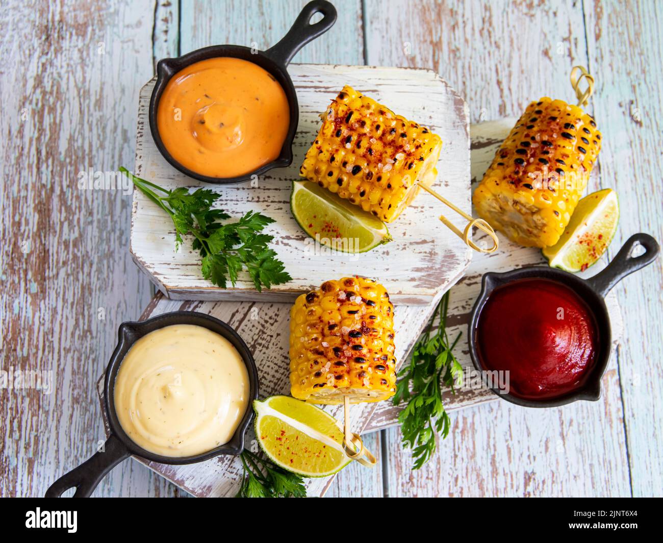 grilled yellow corn with spices lime white red orange sauce portion top view Stock Photo