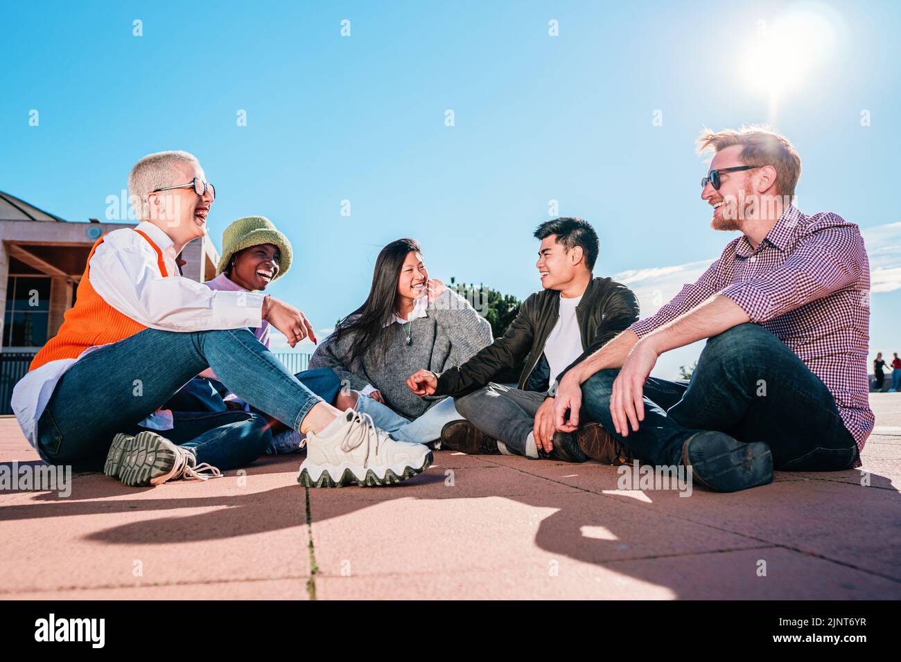 Group of friends sitting on floor laughing and having fun. Stock Photo