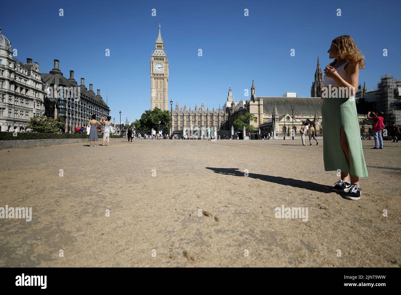 London, Britain. 13th Aug, 2022. A woman stands on the lawn in Parliament Square in London, Britain, on Aug. 13, 2022. A drought was officially declared on Friday across a large swathe of England, amid a new heatwave and prolonged dry weather. Credit: Li Ying/Xinhua/Alamy Live News Stock Photo