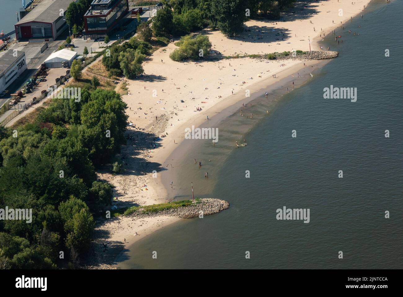 Düsseldorf, NRW, Germany. 13th Aug, 2022. People use the wider sandy beaches to sunbathe and swim in the river. The River Rhine, one of the busiest inland waterways in the world, has been strongly affected by the ongoing drought and resulting low water levels, caused by prolonged heat of up to 40 degrees and very little rain in the last few weeks. The shipping lane has narrowed down considerably, slowing down traffic, most vessels have also had to considerably reduce their freight weight, leading to supply issues and higher shipping prices. Credit: Imageplotter/Alamy Live News Stock Photo