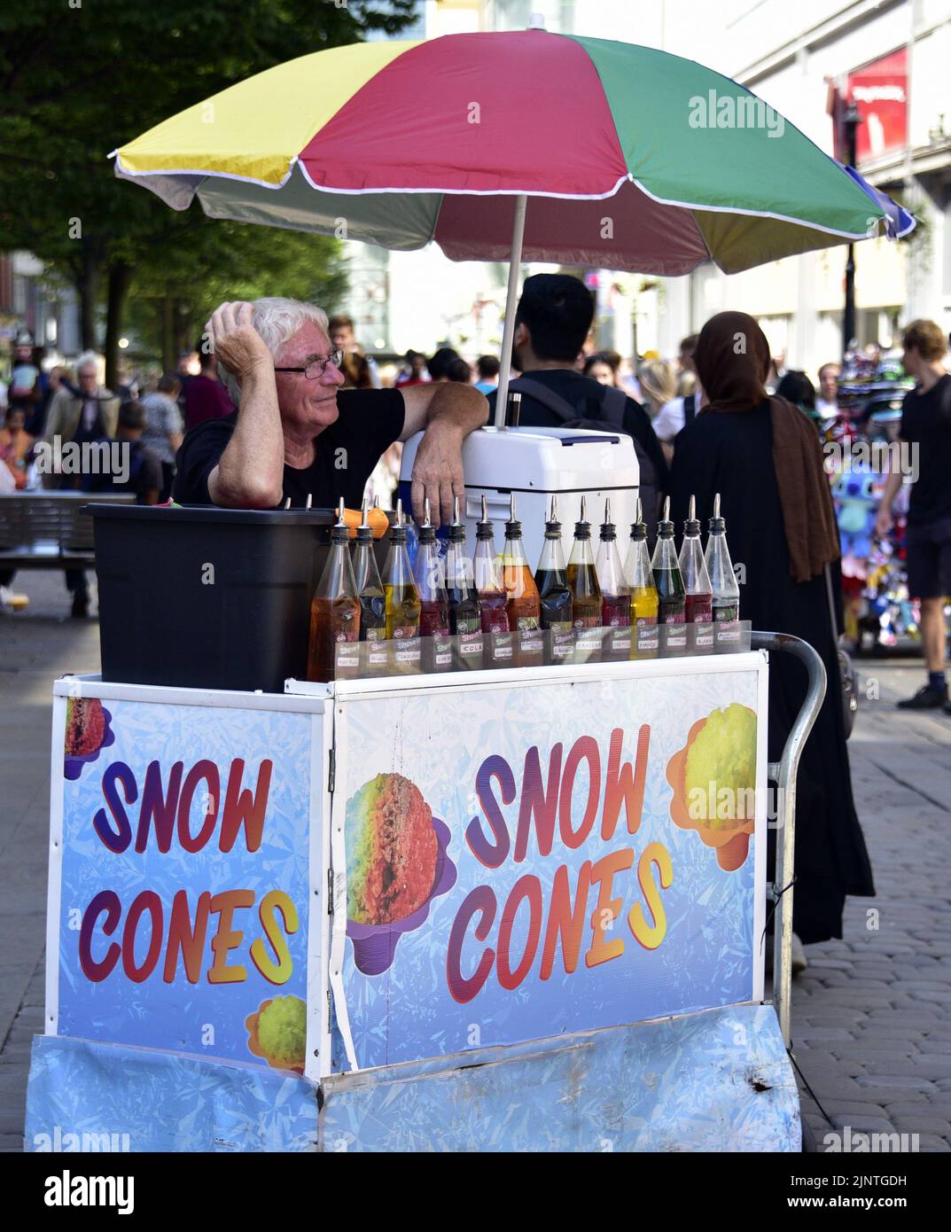 A man selling snow cones at a stall on a hot day on Market Street, central Manchester, United Kingdom, British Isles. Stock Photo