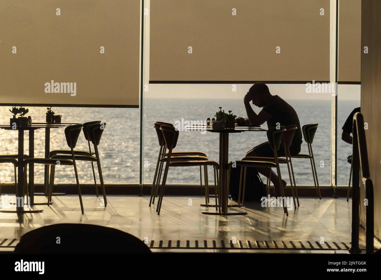 Tel Aviv, Israel. 10th Aug, 2022. A man seen in a coffee house during sunset in Tel Aviv. Tel Aviv, located along the Mediterranean coastline, is Israel's cultural hub and a major travel destination that attracts tourists from around the world. (Credit Image: © Ronen Tivony/SOPA Images via ZUMA Press Wire) Stock Photo