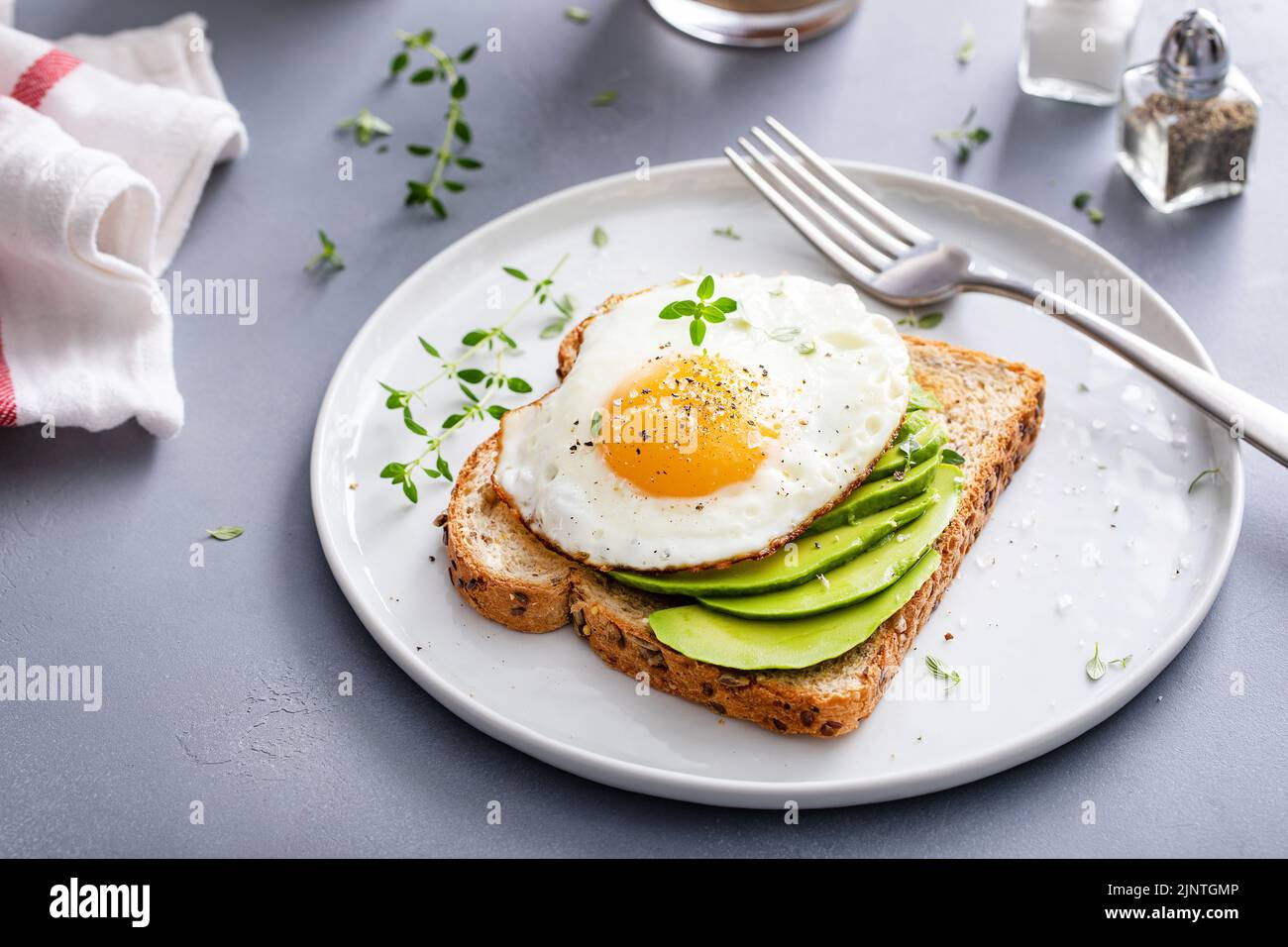 Avocado toast on a toasted multigrain bread with a fried egg Stock Photo