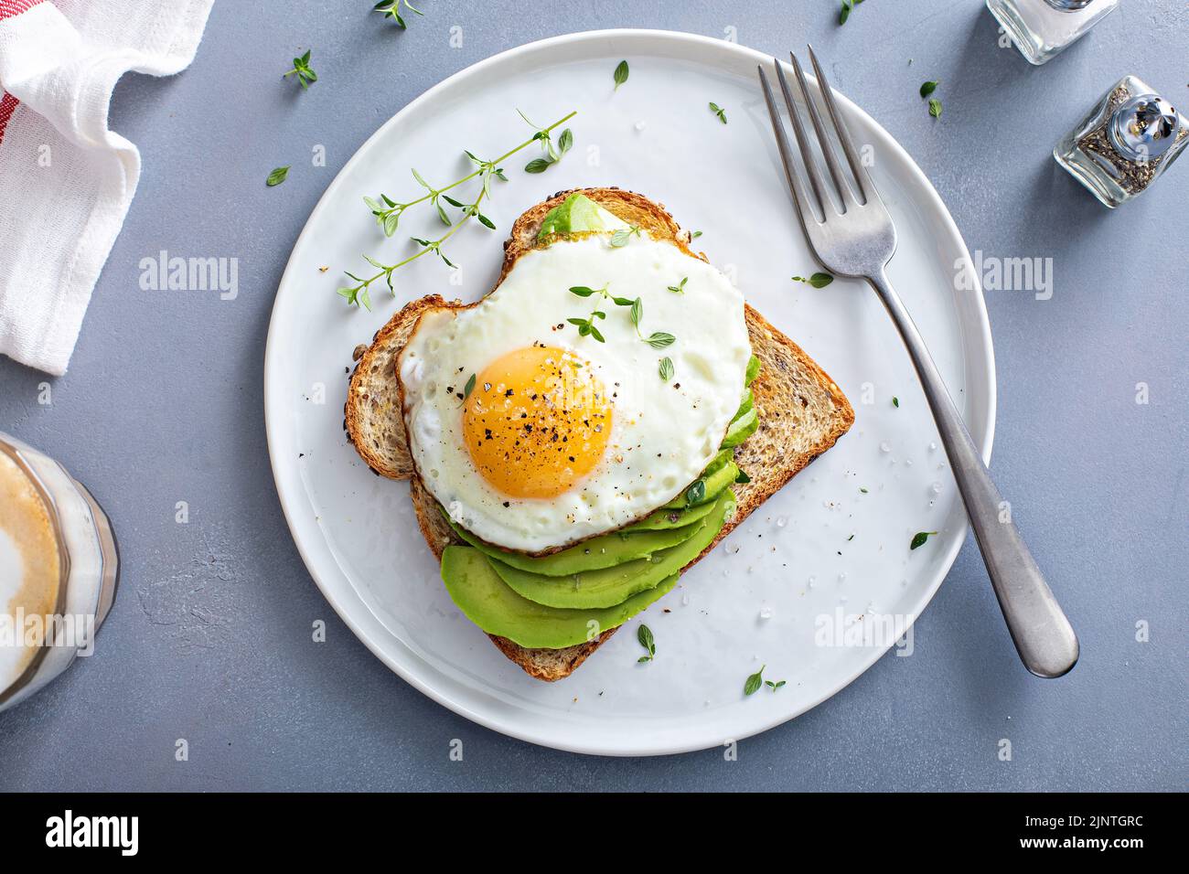 Avocado toast on a toasted multigrain bread with a fried egg Stock Photo