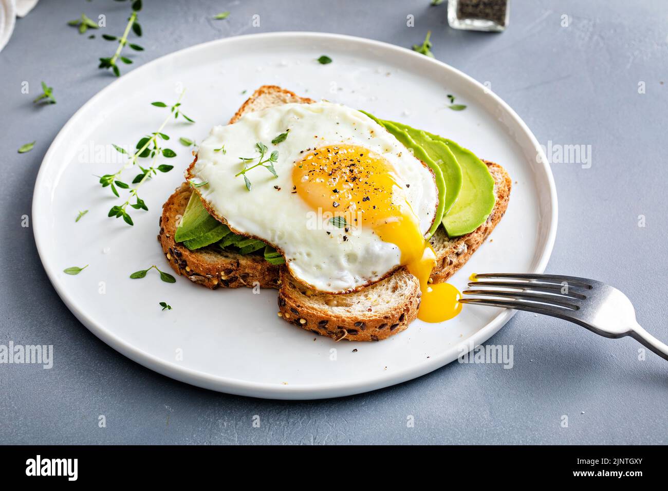 Avocado toast on a toasted multigrain bread with a fried egg Stock Photo