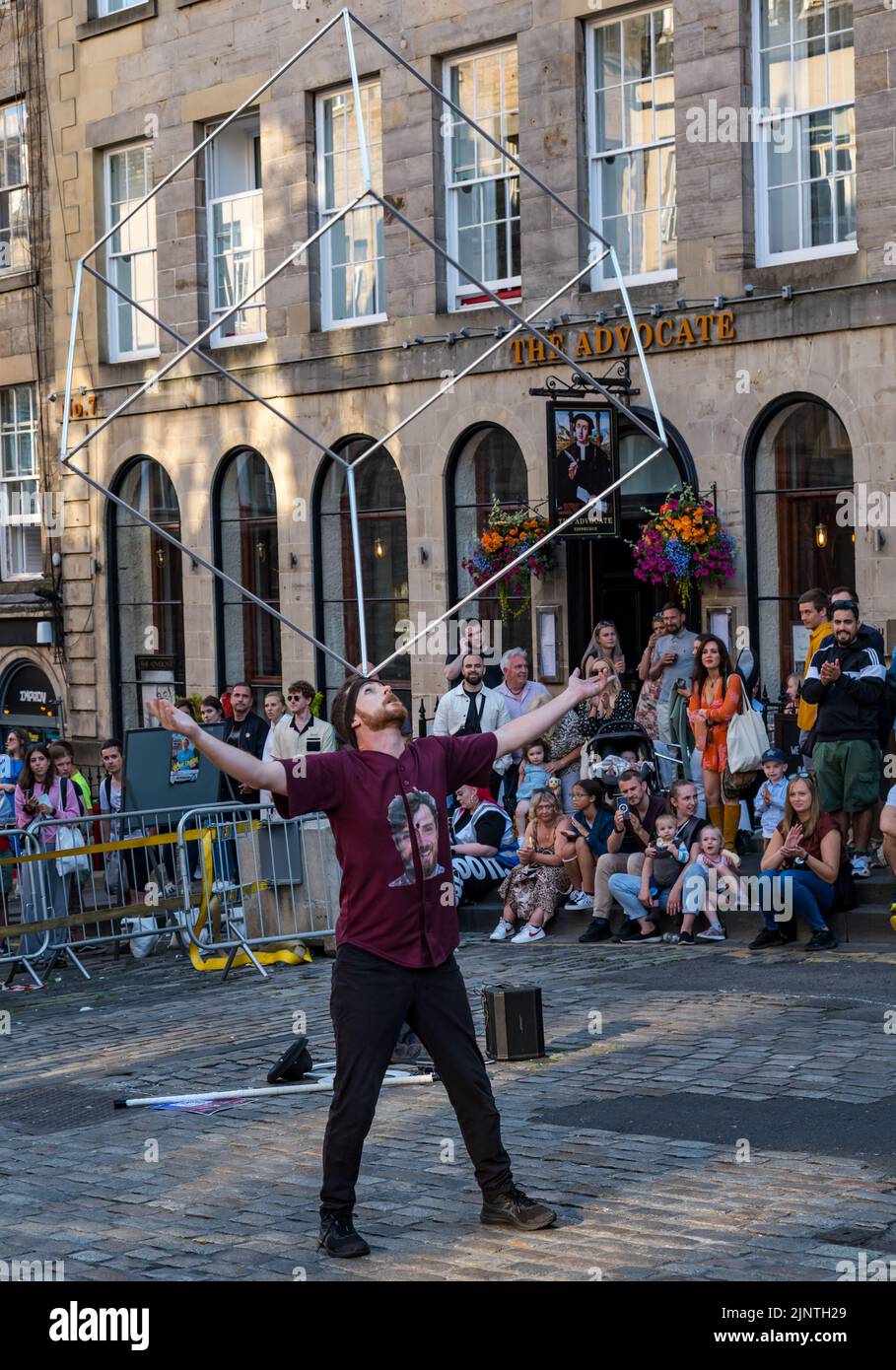 Edinburgh, Scotland, United Kingdom, 13th August 2022. Edinburgh Fringe entertainment: a street performer entertains the crowd with a balancing act Stock Photo