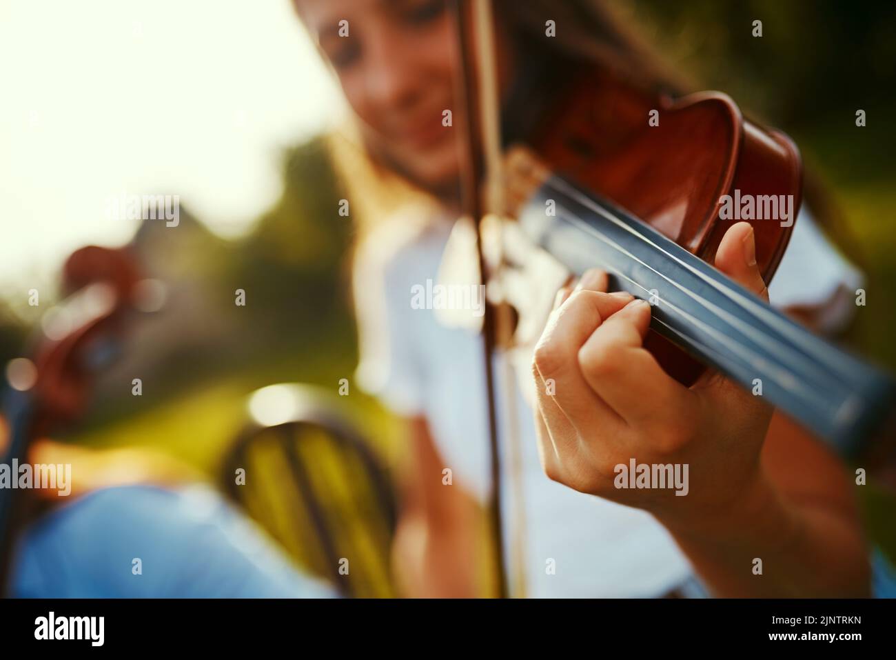 Its all about following the notes. a young girl playing a violin outdoors. Stock Photo