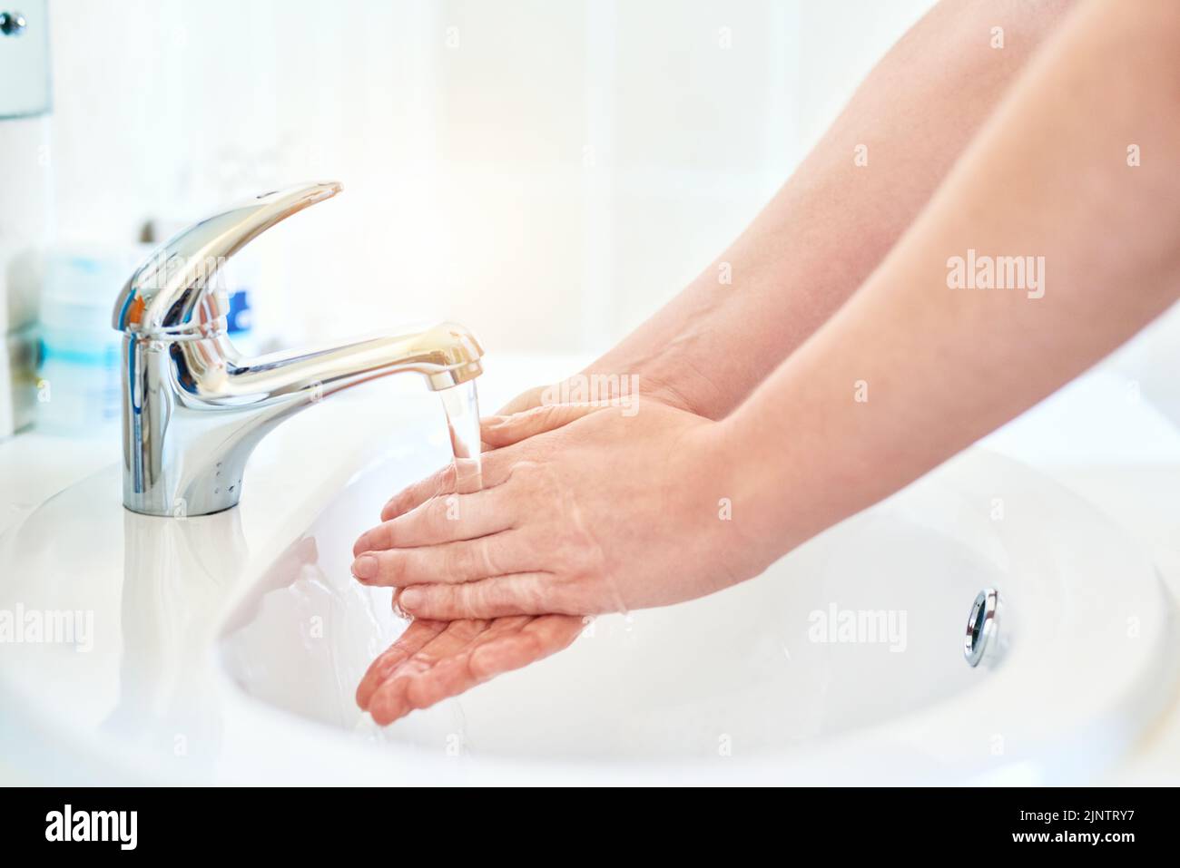 Every drop counts. Closeup shot of an unrecognizable woman washing her hands in the basin in the bathroom at home. Stock Photo