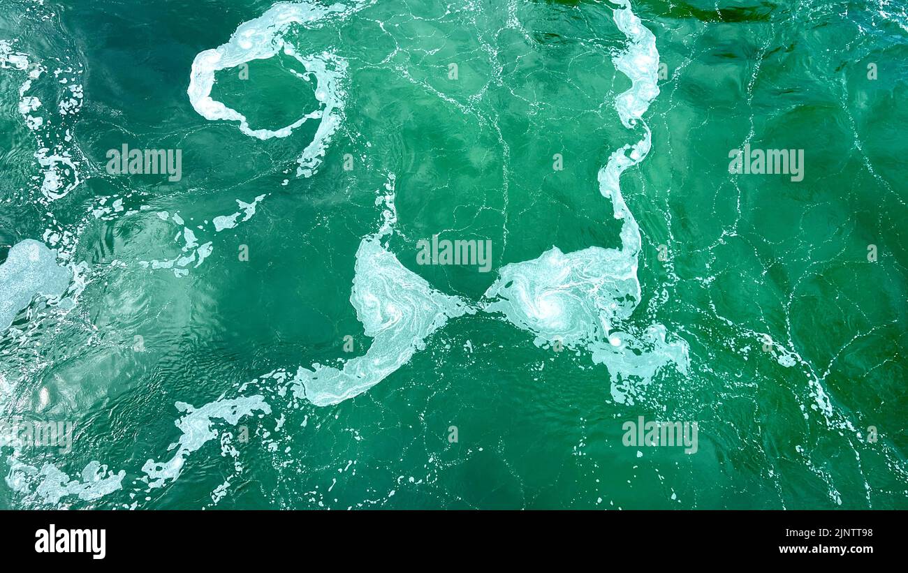white streaks on the emerald green water of a river or ocean is perfect For text for the beginning of an advertising film, life is seething empty space For text room decoration picture. High quality Stock Photo