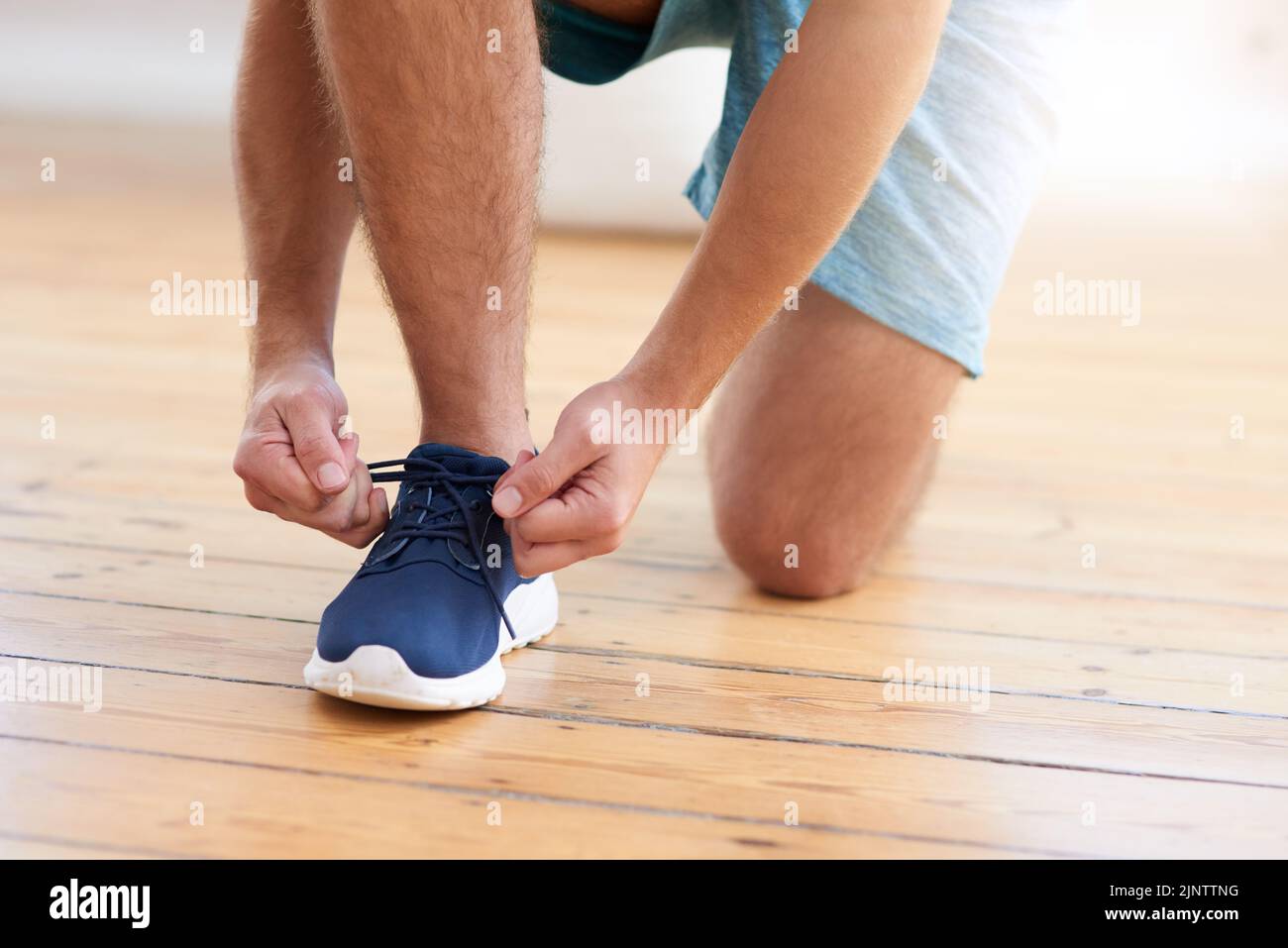 Lace up and lets get running. a man tying his shoelaces in a gym. Stock Photo