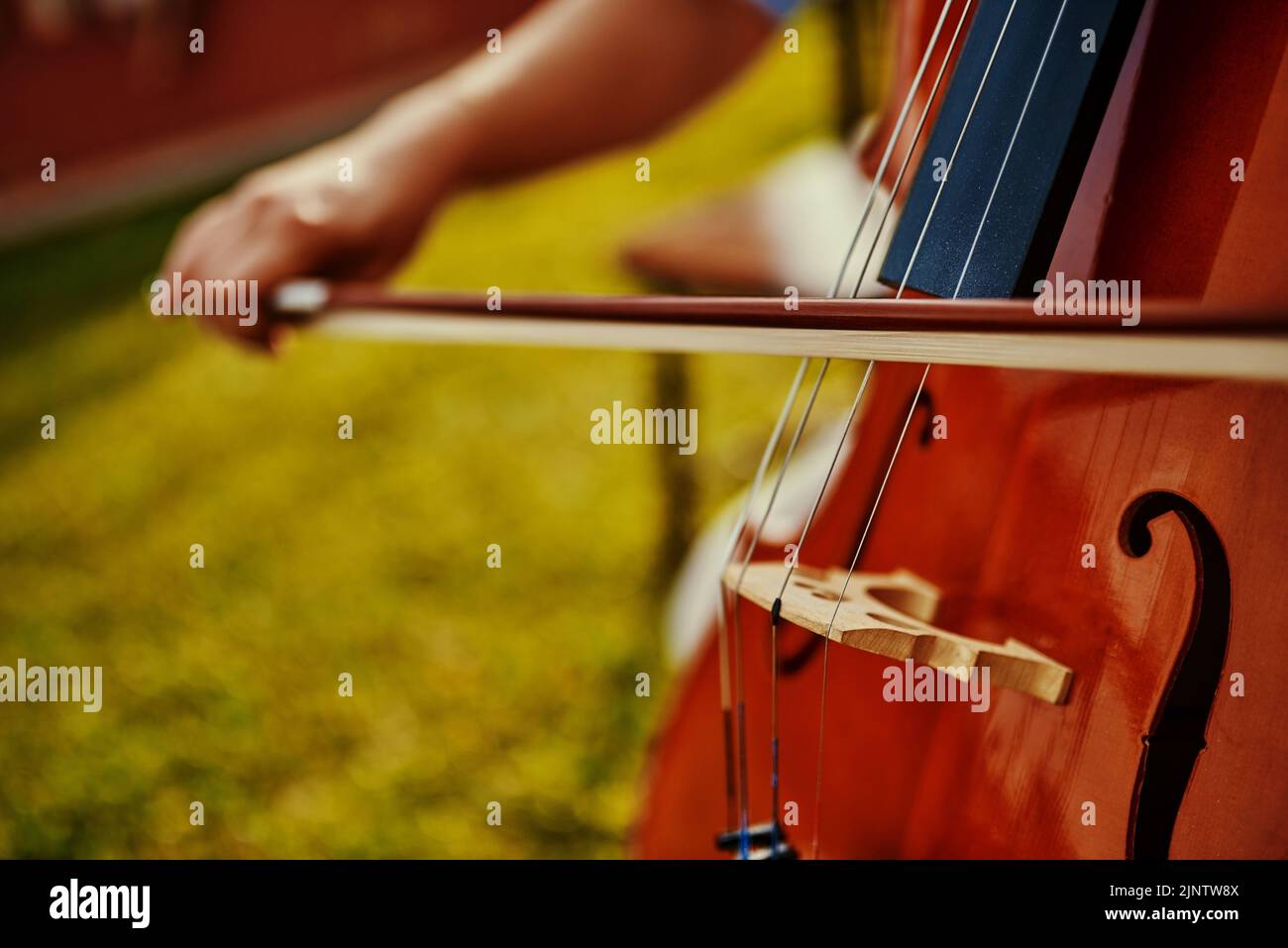 Practice always makes perfect. an unrecognizable woman playing a cello outdoors. Stock Photo