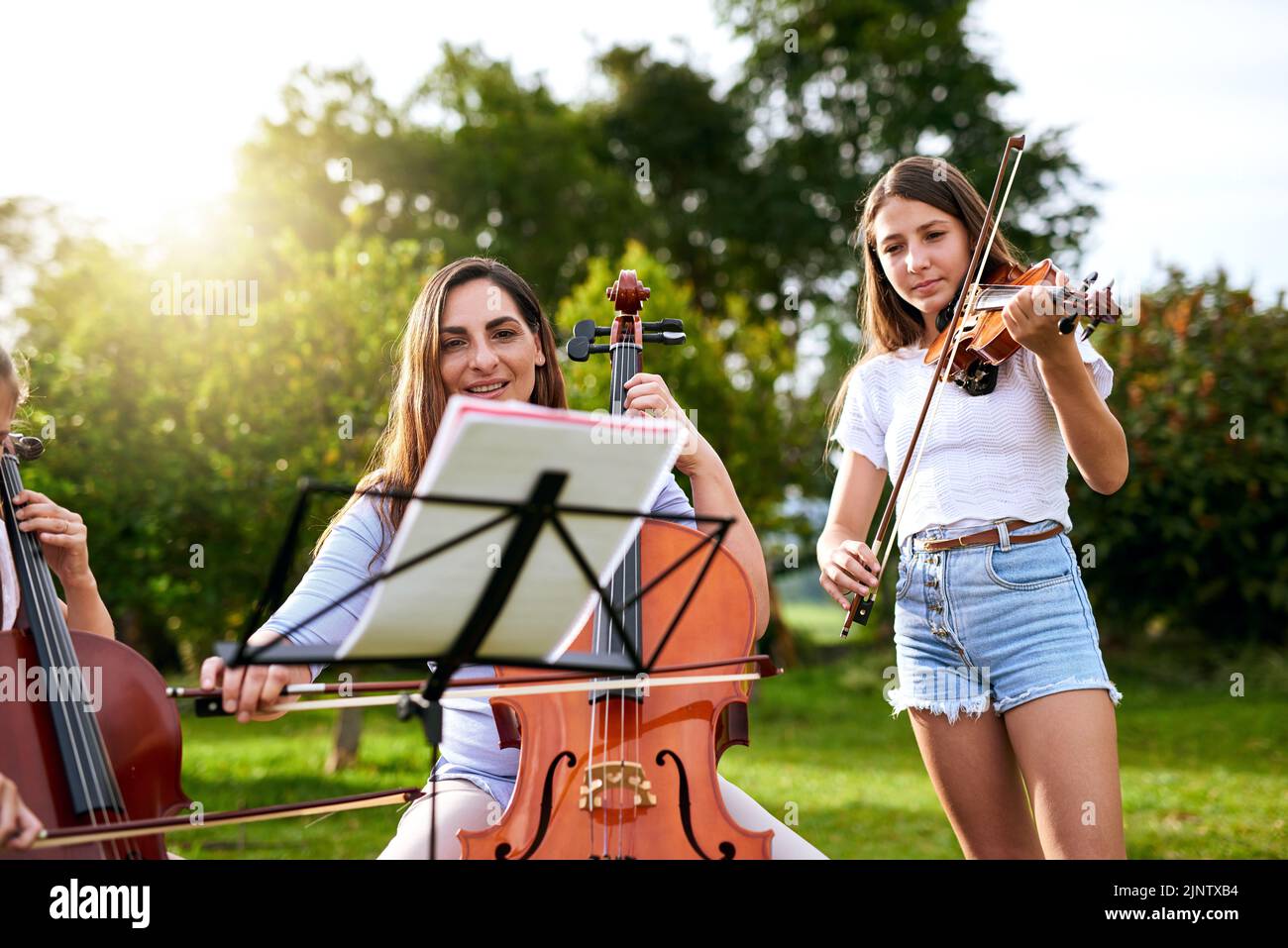Definitely one of our most favorite pastimes. a young girl playing a violin outdoors. Stock Photo