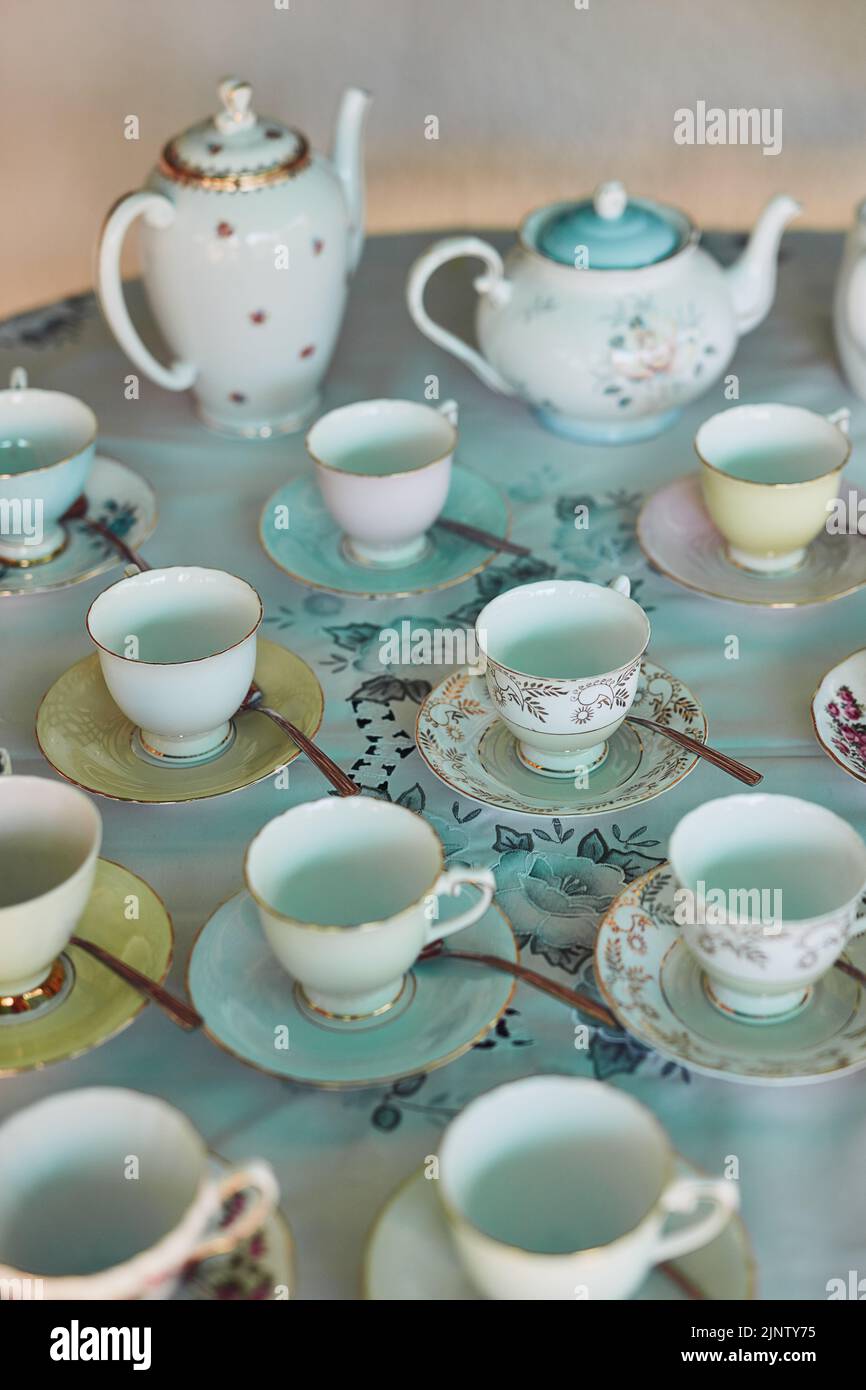 The table is set, time to begin the tea party. tea pots and tea cups laid out on a table at a tea party inside. Stock Photo