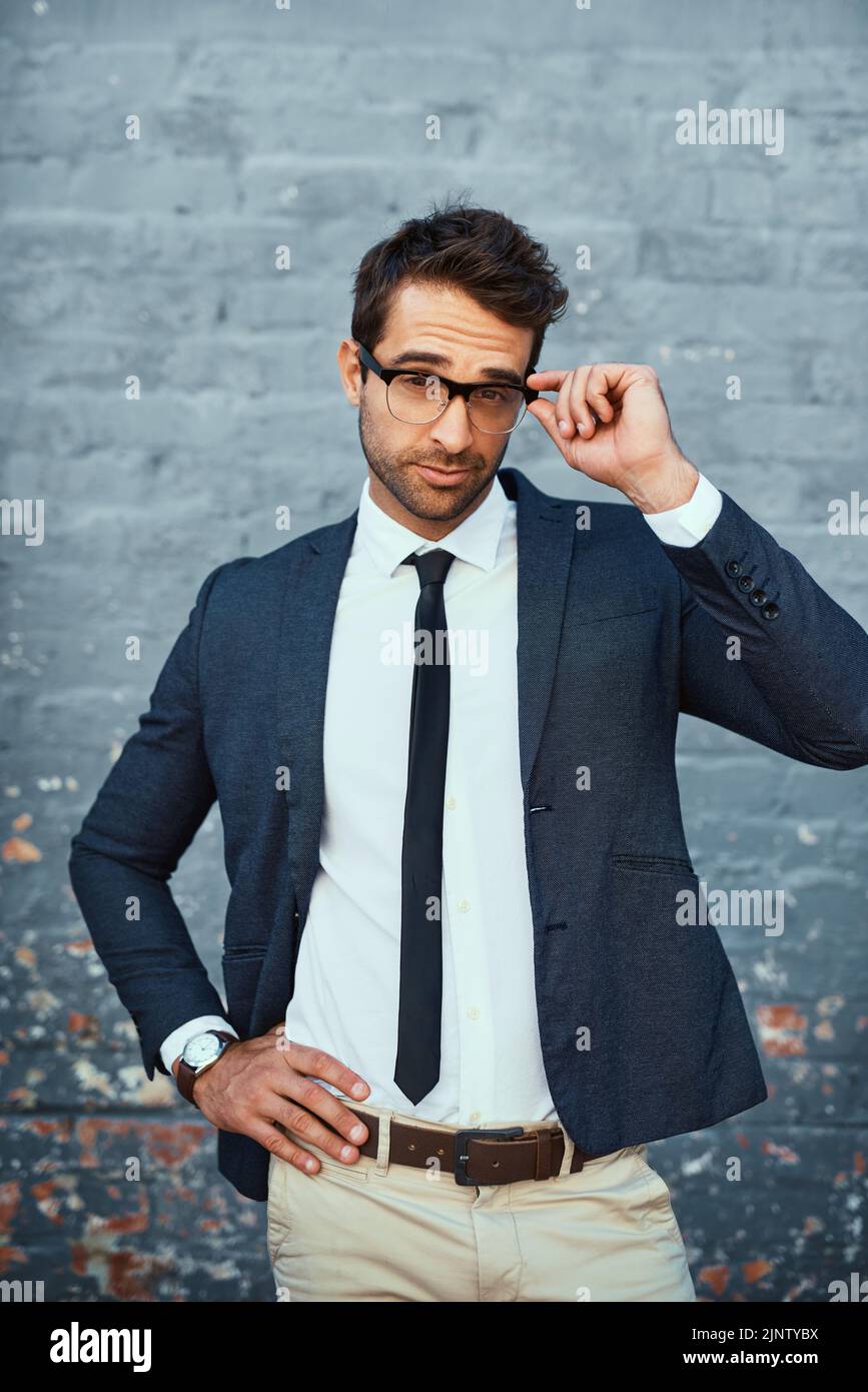 Not all business is done in the office. Cropped portrait of a handsome young businessman standing with his hand on his hip against a grey facebrick Stock Photo