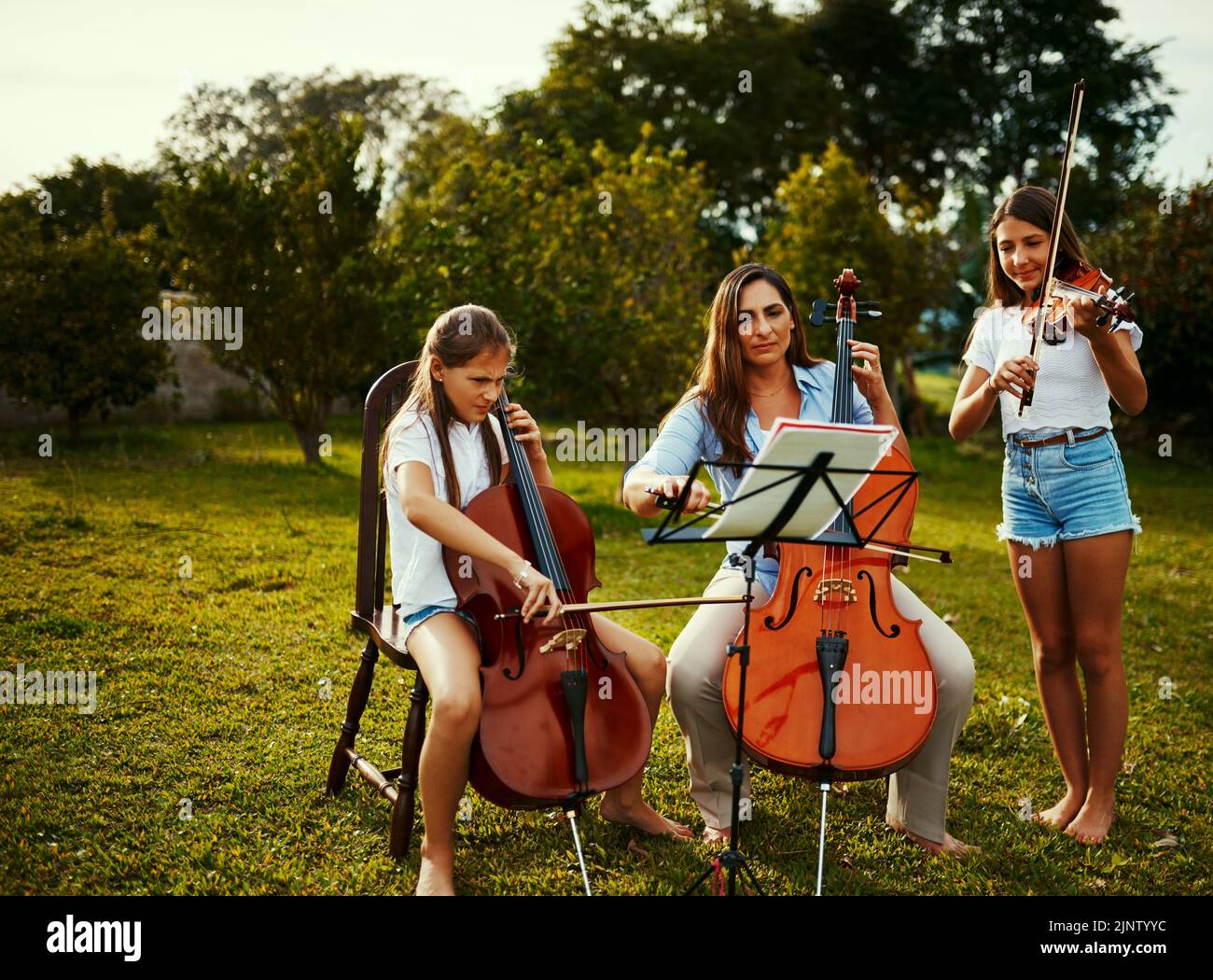 Moms the master musician and we follow her lead. a beautiful mother playing instruments with her adorable daughters outdoors. Stock Photo