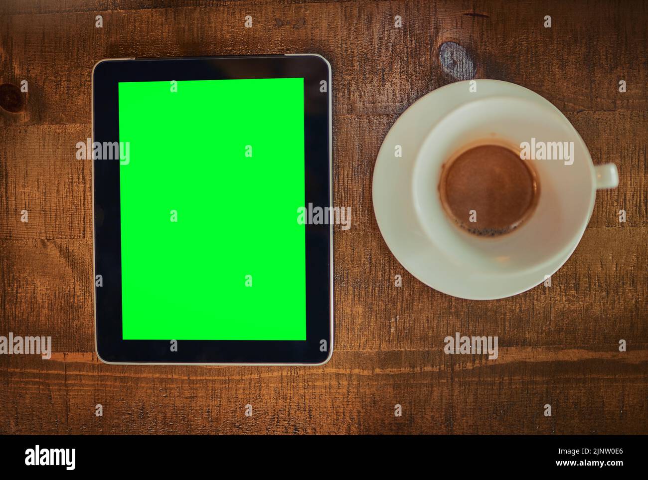 Coffee and wifi Yes please. High angle shot of a digital tablet with a green screen and cup of coffee on a table. Stock Photo