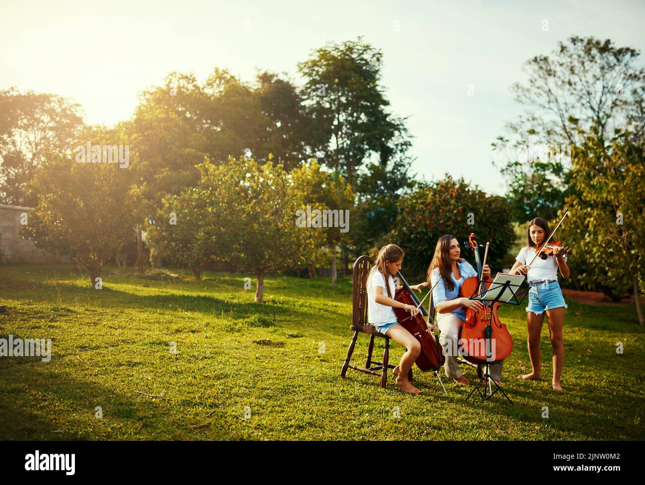 Her favourite part of the week, practicing with her girls. a beautiful mother playing instruments with her adorable daughters outdoors. Stock Photo
